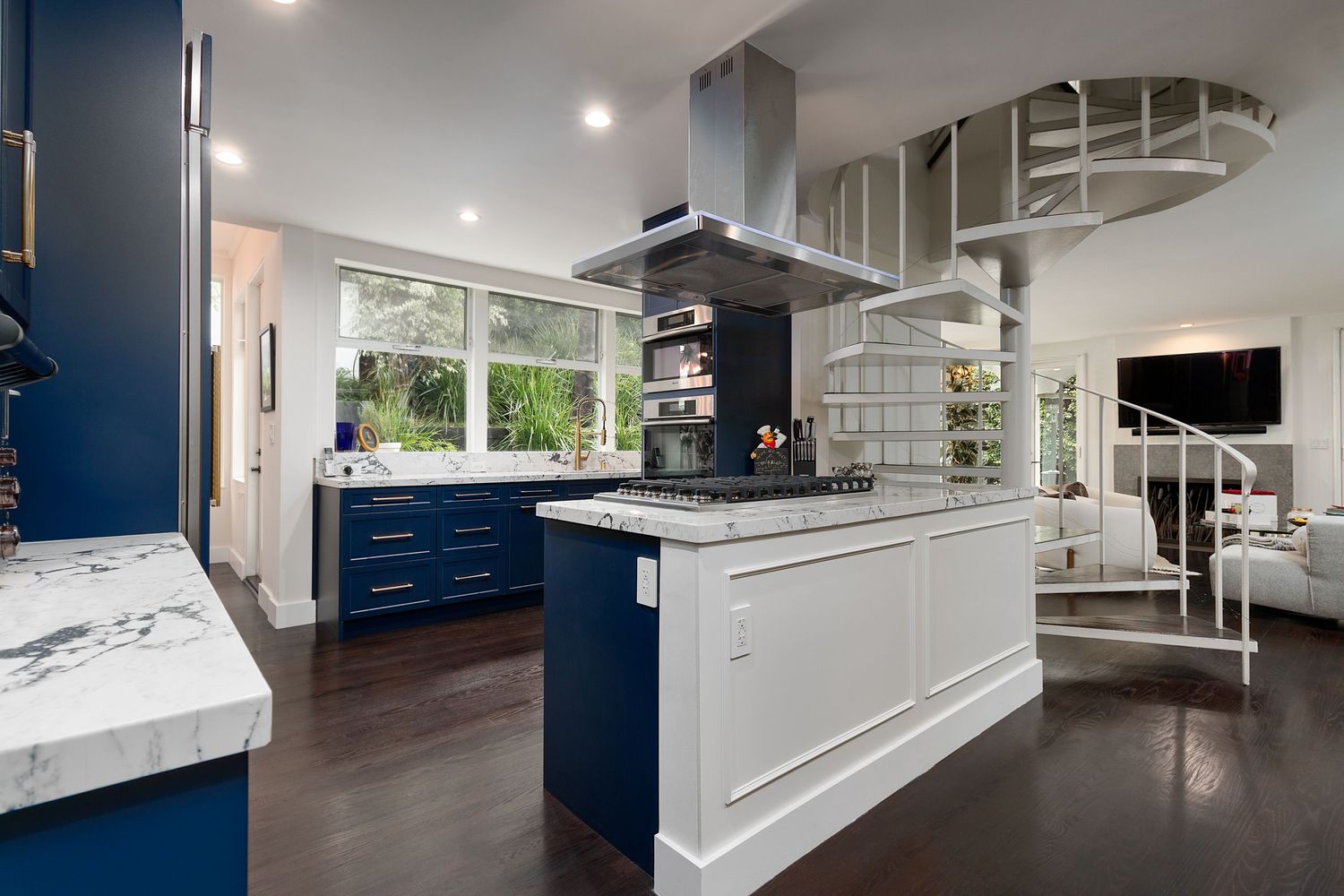 Modern kitchen with navy blue cabinets, white countertops, and stainless steel appliances.
