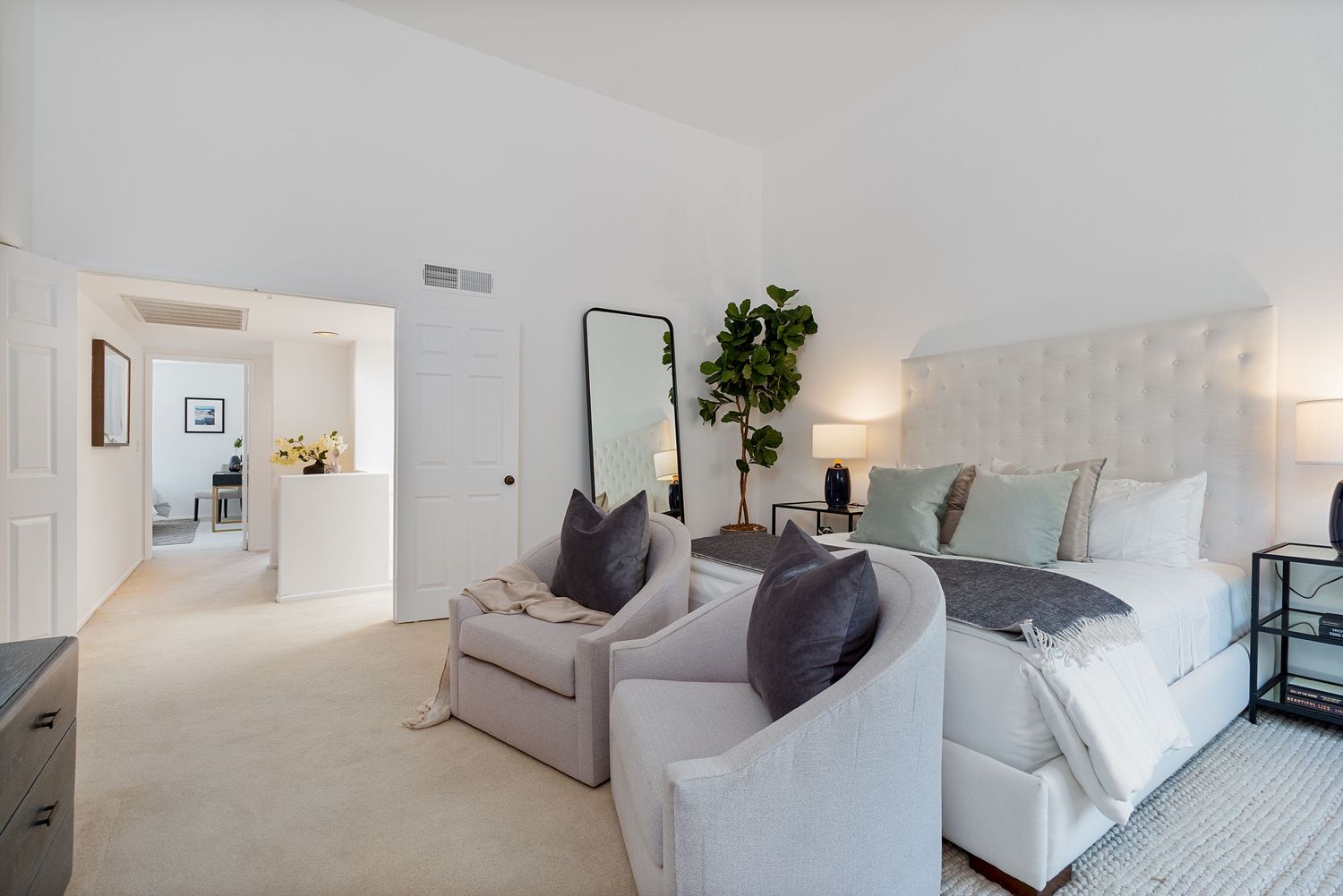 Bright modern bedroom with gray and white decor, featuring plush bedding and minimalist design.