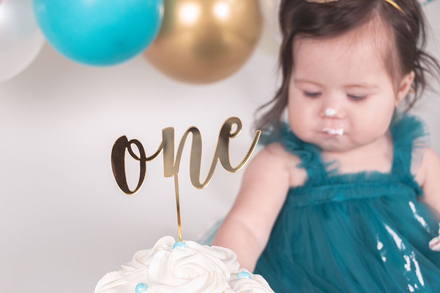 Festive birthday setup with turquoise balloons and gold accents against a light backdrop.