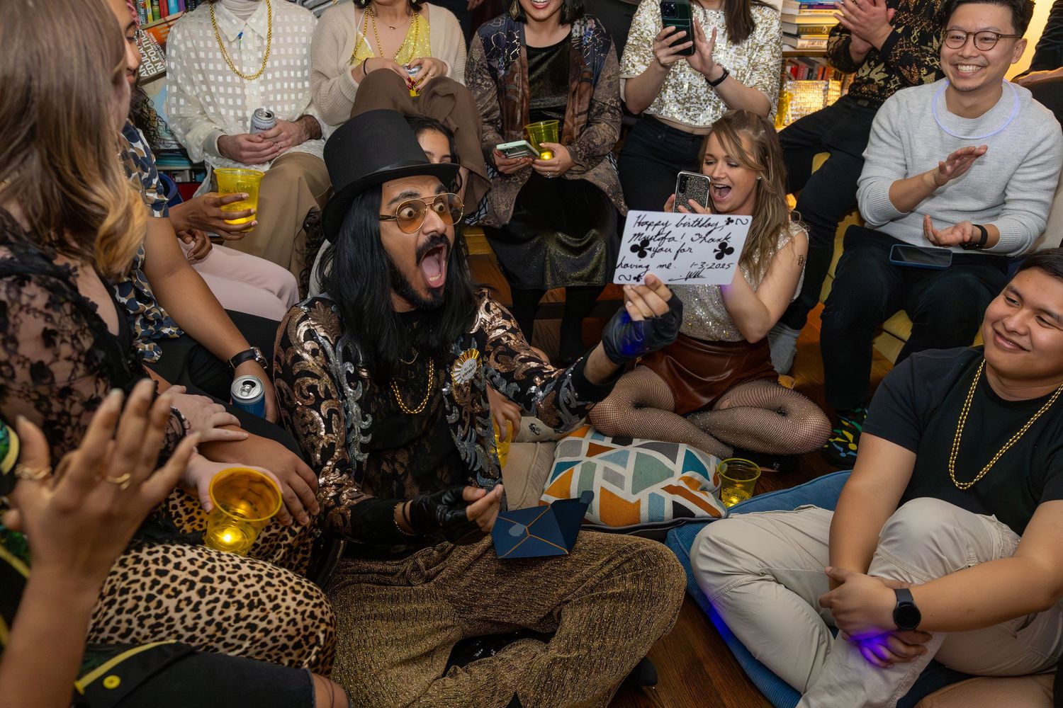 Candid event photograph of birthday party guests watching a magician perform a magic show.