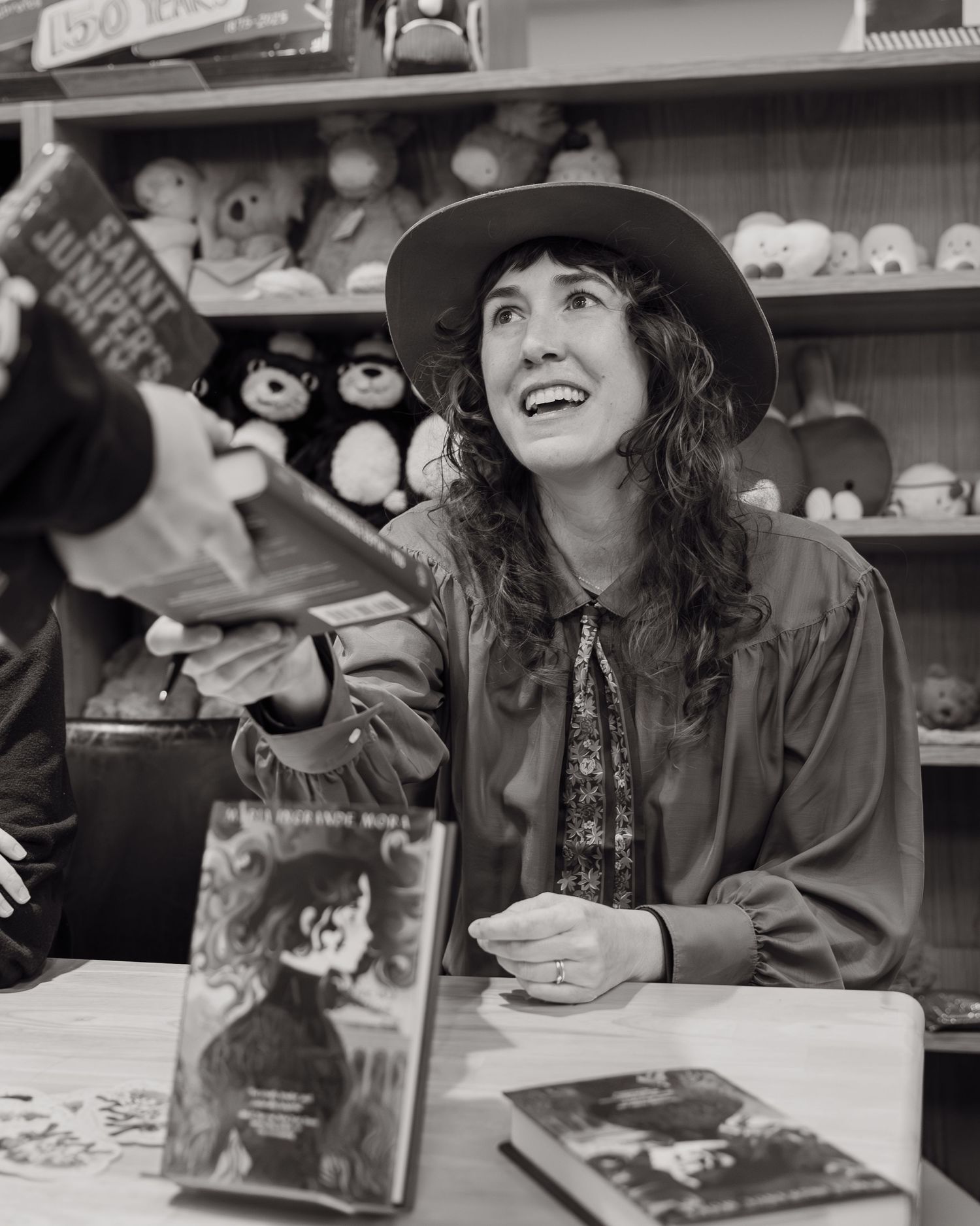 Candid event photograph of an author signing books for attendees during a book launch event.