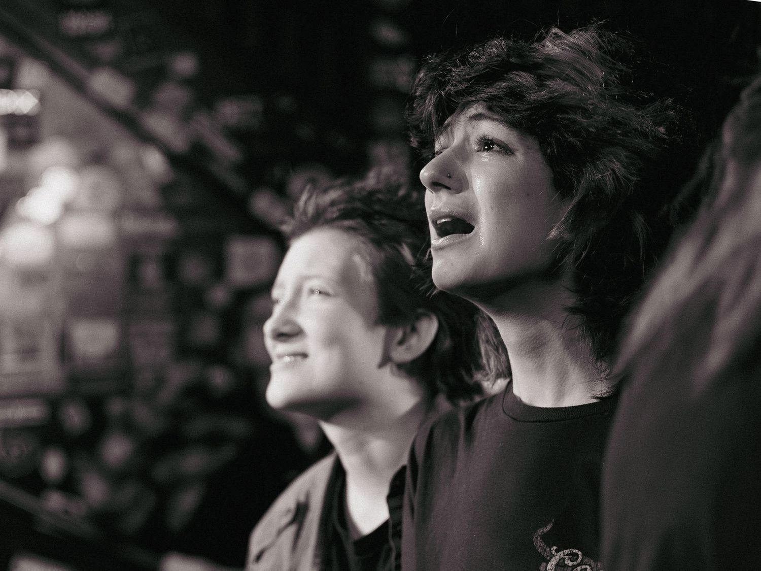 Candid concert portrait of an audience member crying during an emotional live music performance.
