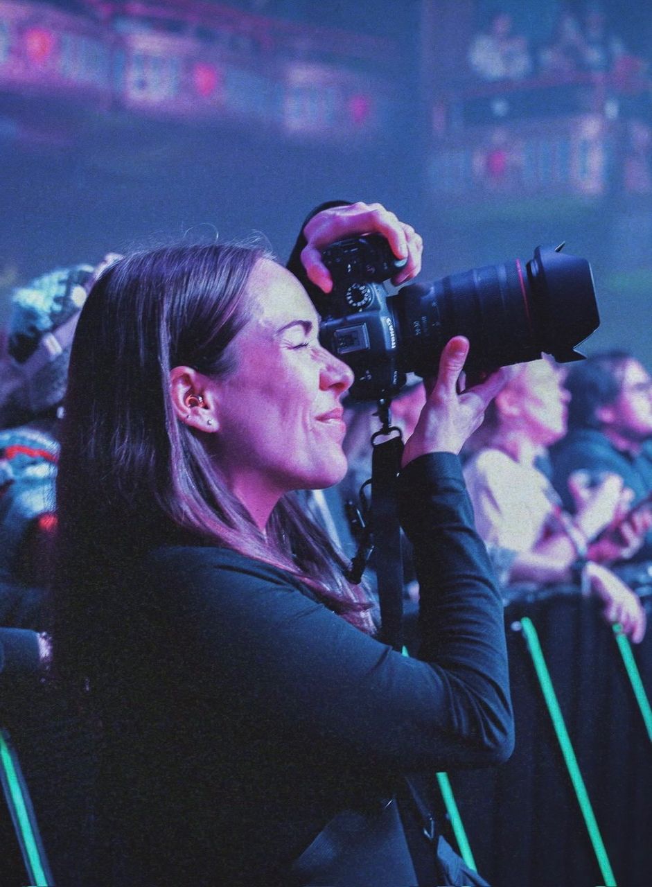 Photographer Andrea Ingrande holding a camera, illuminated by vibrant purple and blue lighting.