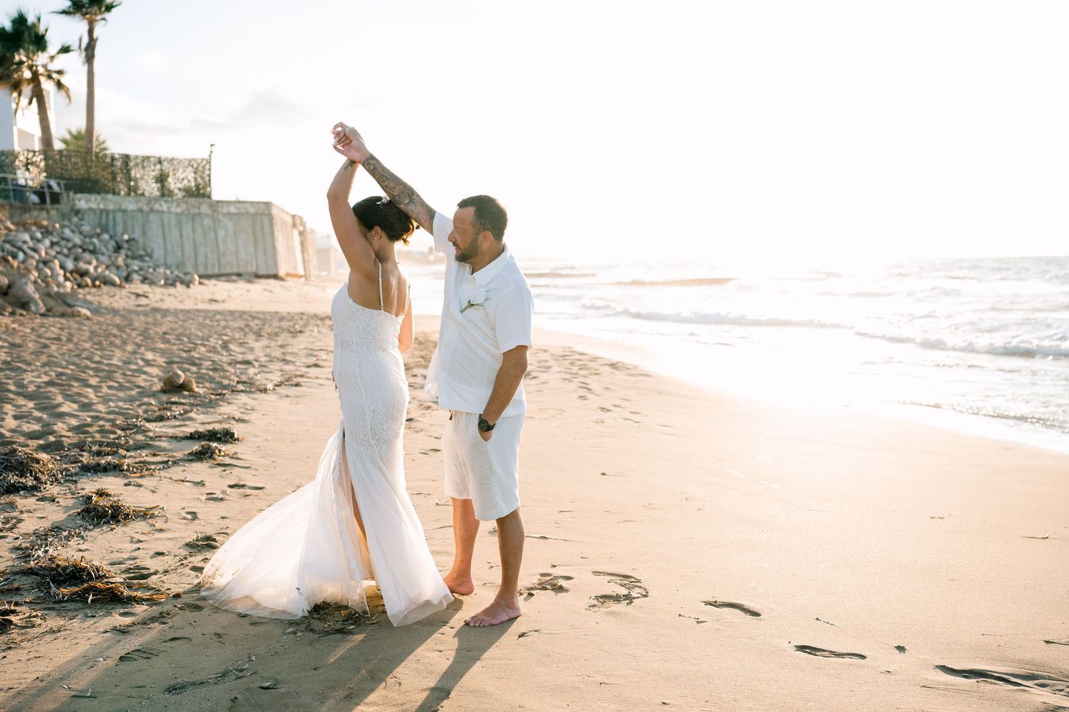 Bride and groom dancing on the beach in warm evening light, light and airy destination wedding photography in Crete