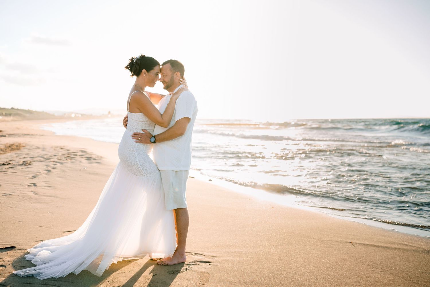Couple embracing forehead to forehead on the beach in soft golden light, elegant elopement in Crete