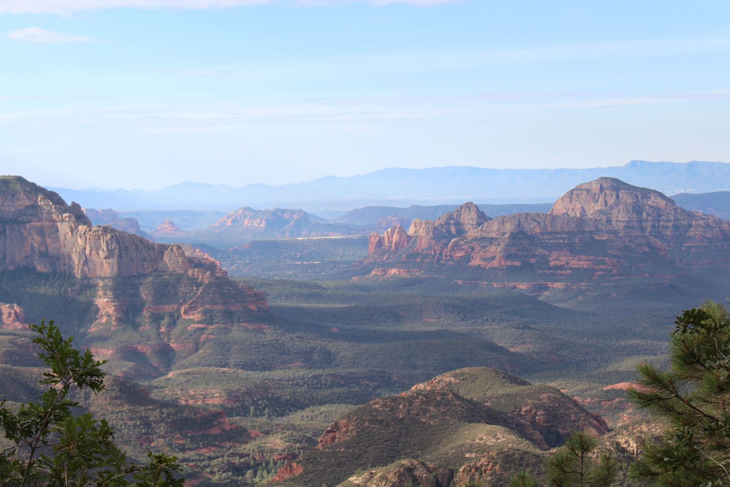 Panoramic view of Sedona, Arizona red rock formations and desert valley landscape under a clear blue sky.