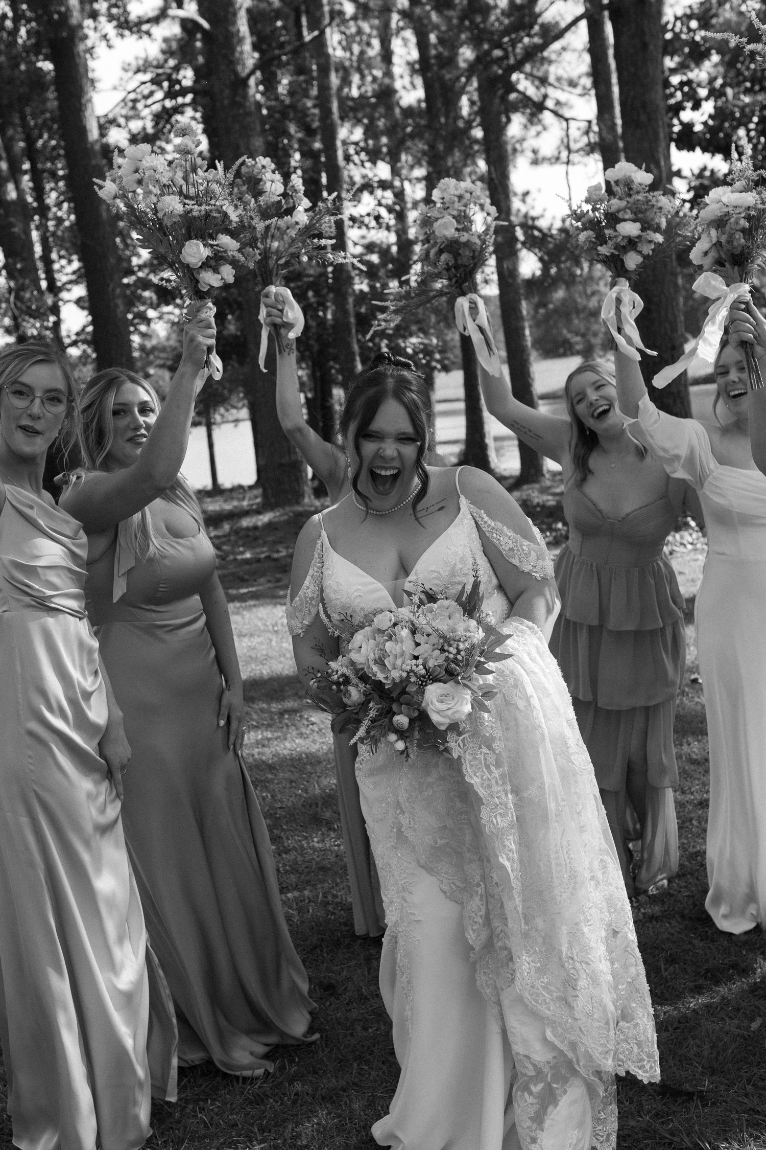 A bride and her girls dance and celebrate with their bouquets on the bride's north georgia lakeside elopement day