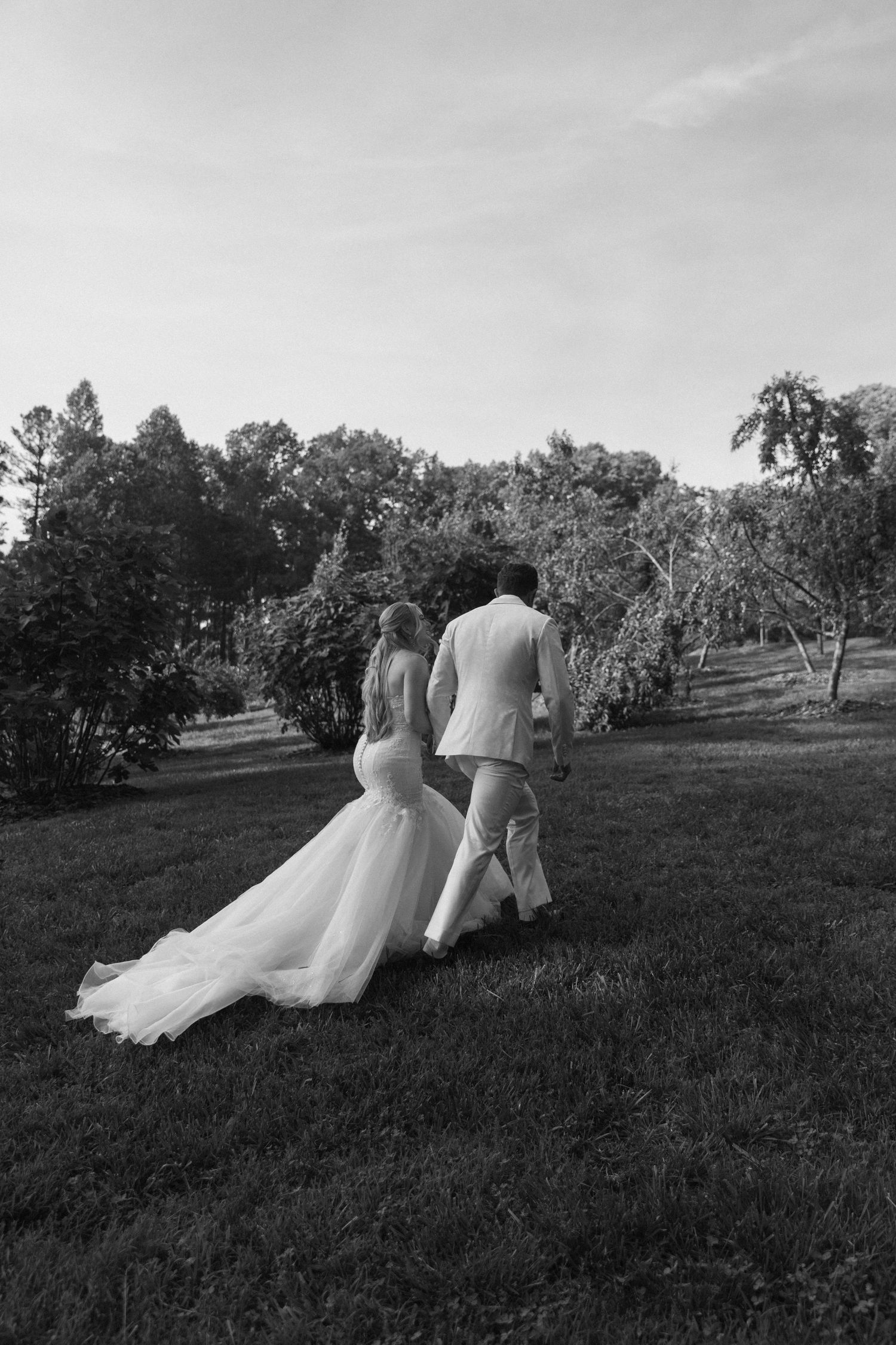 Couple walks up the grassy hillside vineyard at their intimate ellijay elopement