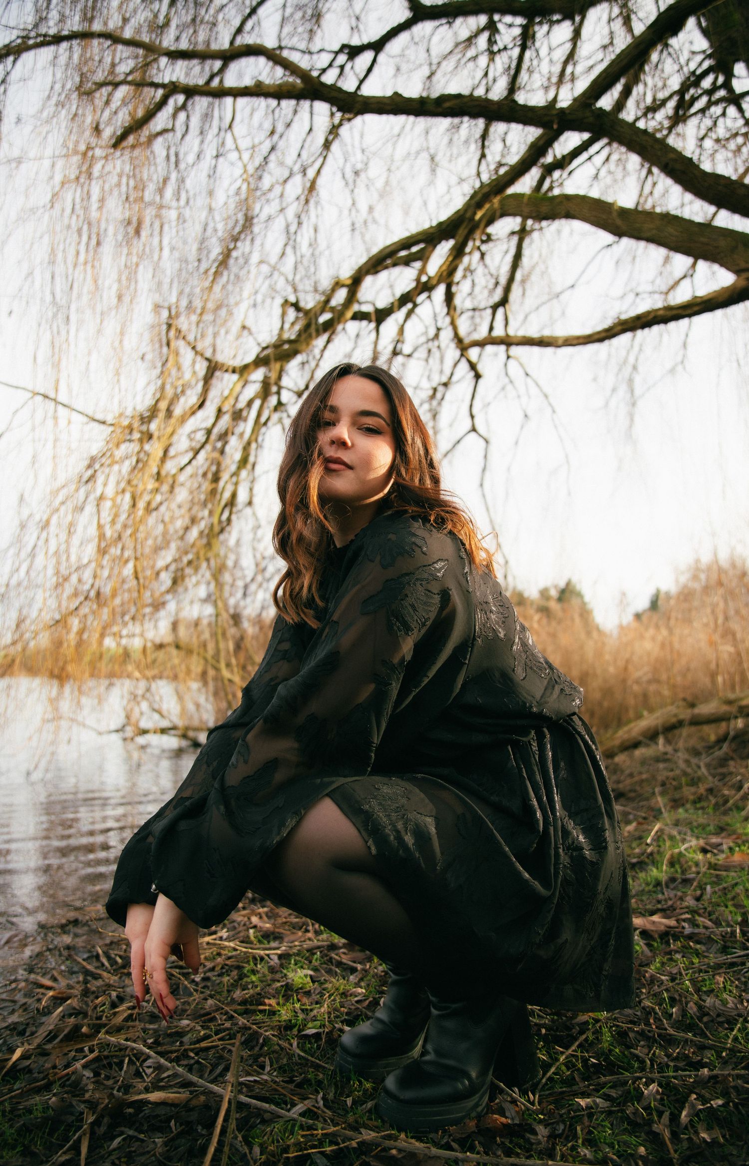 Photographe Essonne 91, portrait de jeune femme au manteau sombre regardant l'objectif, ambiance hivernale et naturelle au bord de l'eau