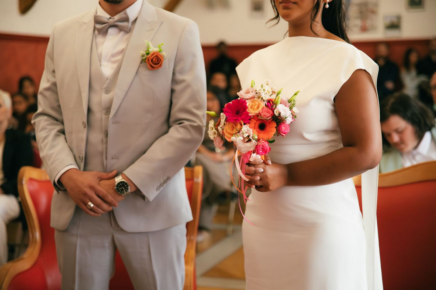 Photographe mariage Essonne 91, mariés côte à côte en cérémonie civile, costume gris et nœud papillon, robe blanche et bouquet coloré