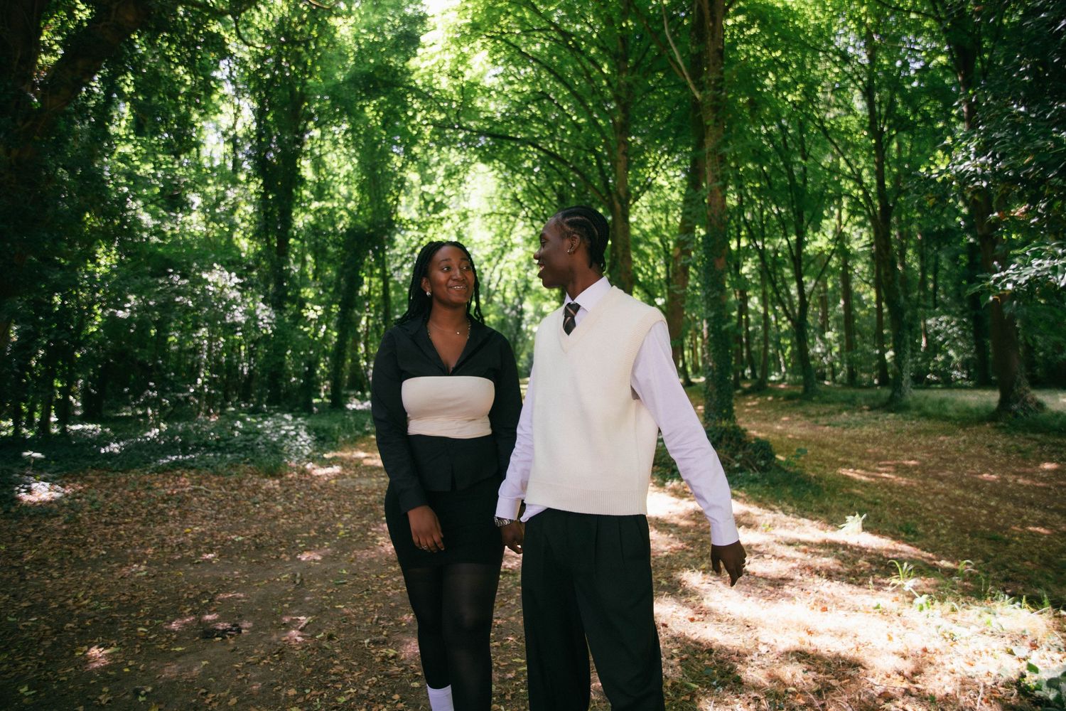 Séance photo couple complice se promenant main dans la main en forêt ensoleillée, photographe couple Essonne 91