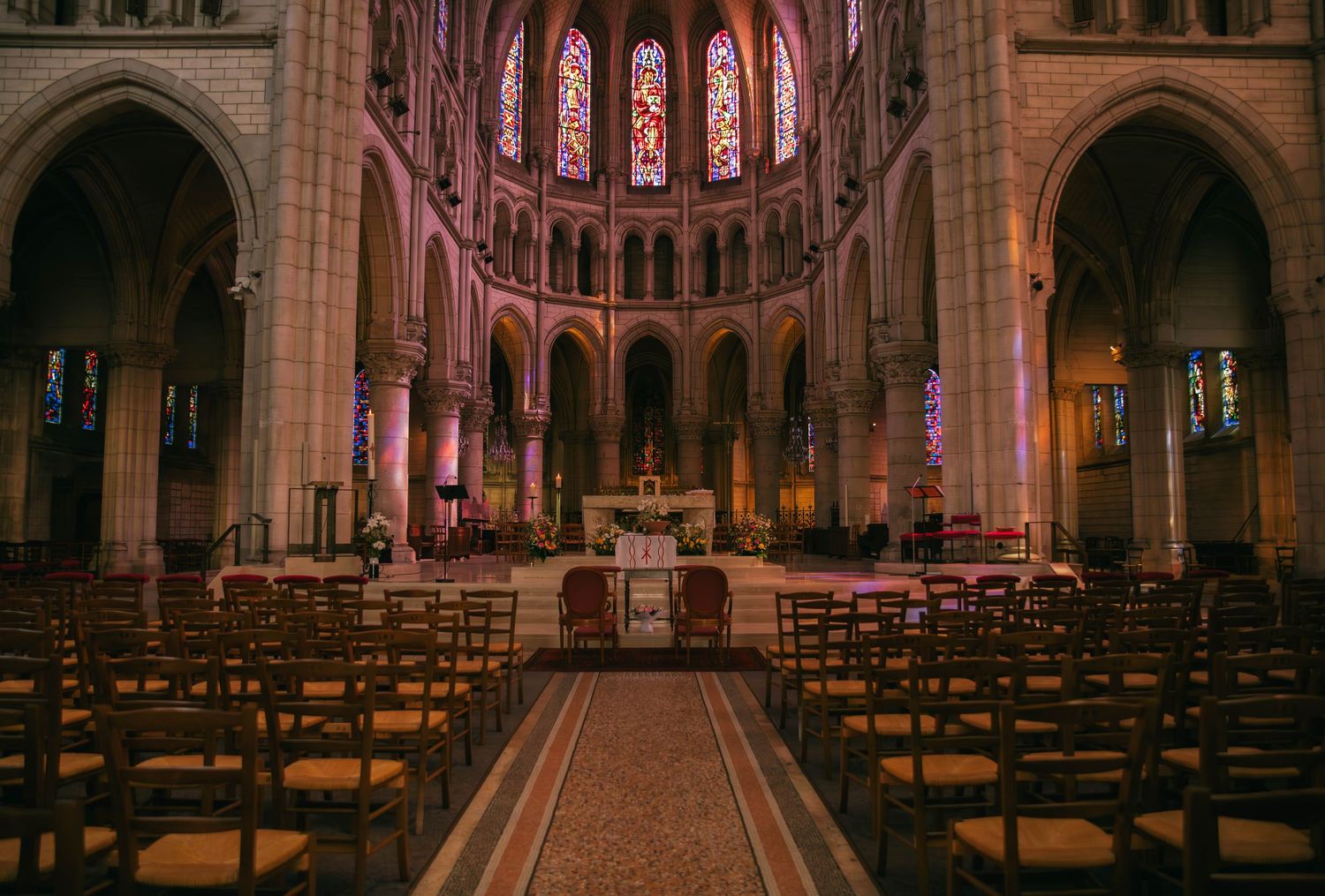 Photographe mariage Essonne 91, intérieur d'une cathédrale gothique aux vitraux colorés avant cérémonie religieuse, reportage mariage
