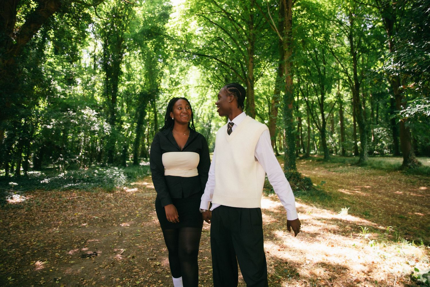 Séance photo couple complice se promenant main dans la main en forêt ensoleillée, photographe couple Essonne 91