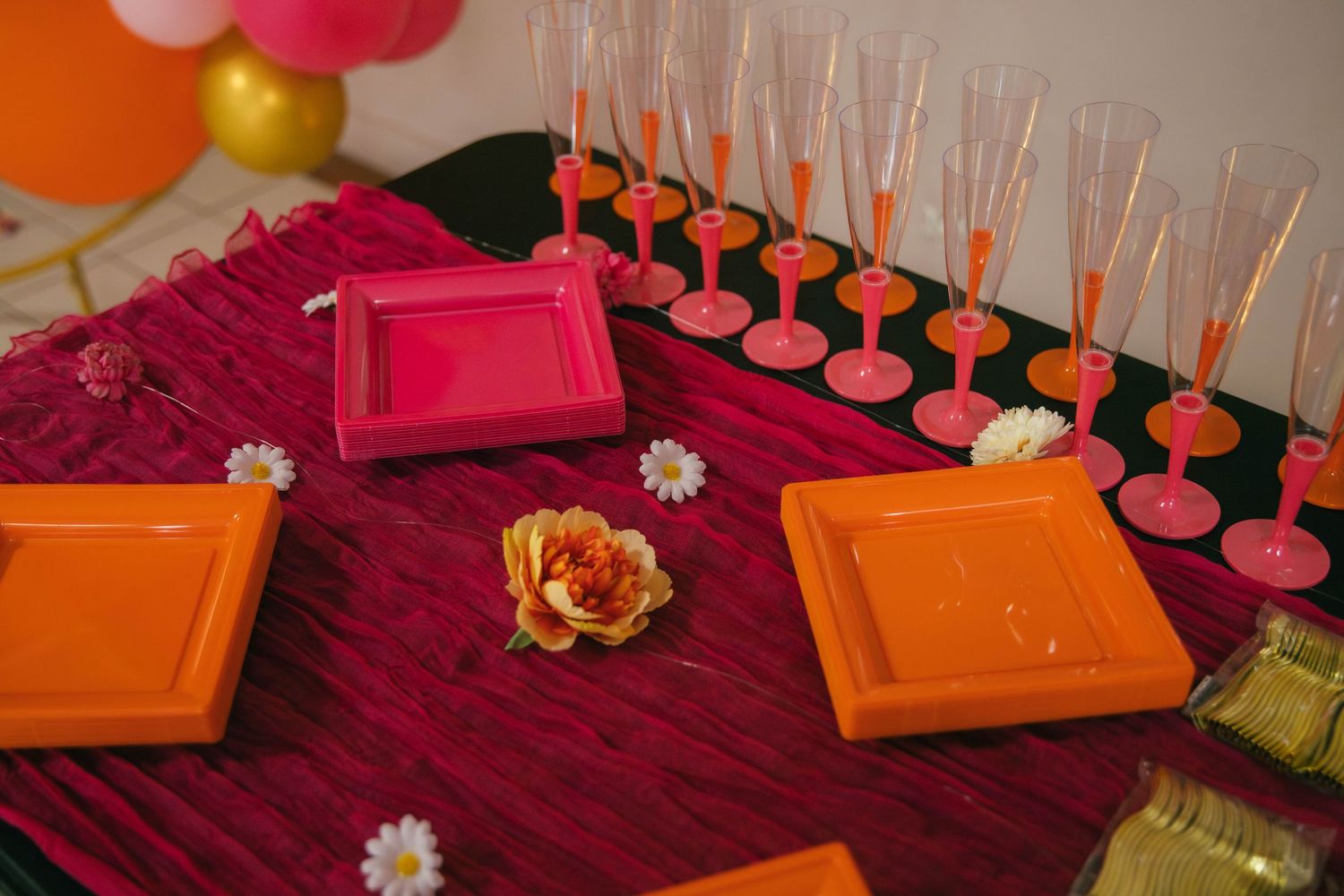 Table de fête colorée en orange et rose vif, flûtes de champagne et décoration florale festive. Reportage événement en Essonne. Photographe
