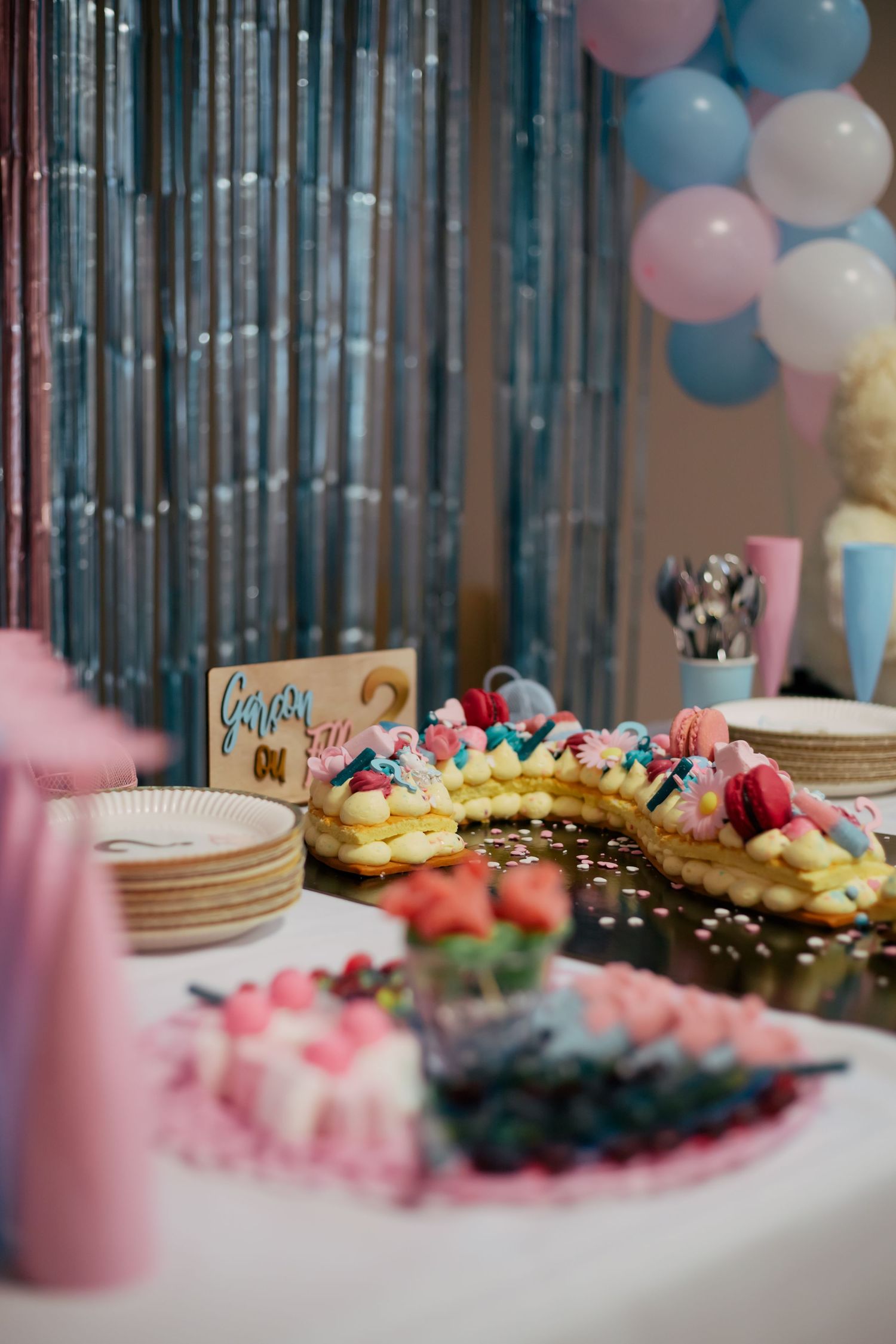 Table sucrée de gender reveal avec number cake, macarons et ballons bleu et rose. Reportage événement et famille en Essonne. Photographe 91.