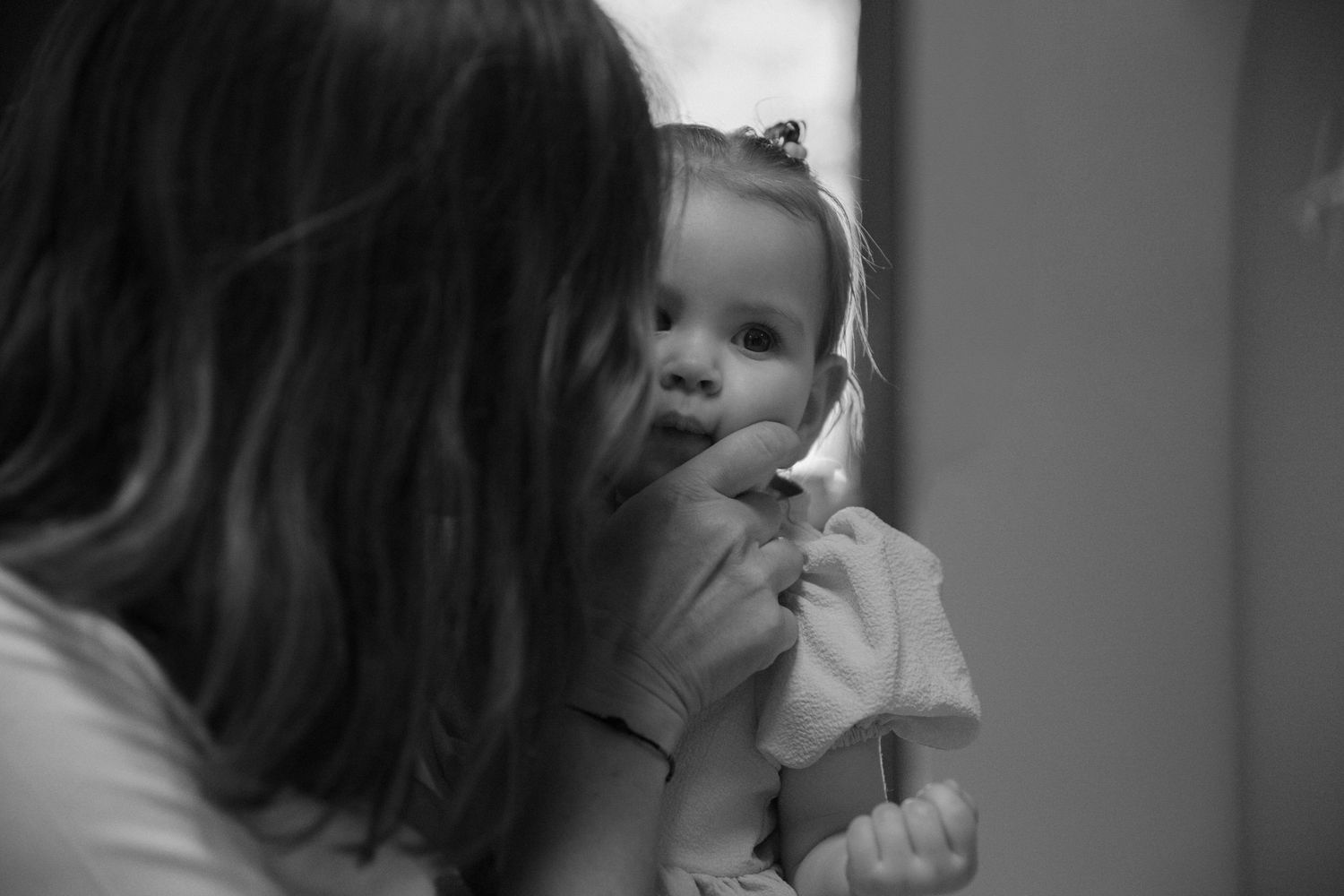 Instant de tendresse Essonne 91, mamie embrassant la joue de son bébé aux grands yeux curieux, noir et blanc, séance photo naissance intime