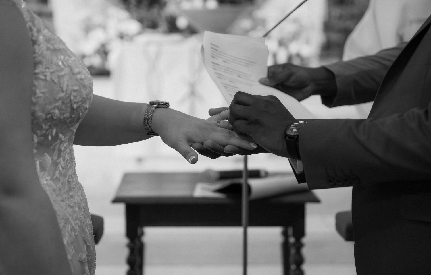 Photographe mariage Essonne 91, échange des alliances en gros plan noir et blanc, mains des mariés unies lors de la cérémonie religieuse