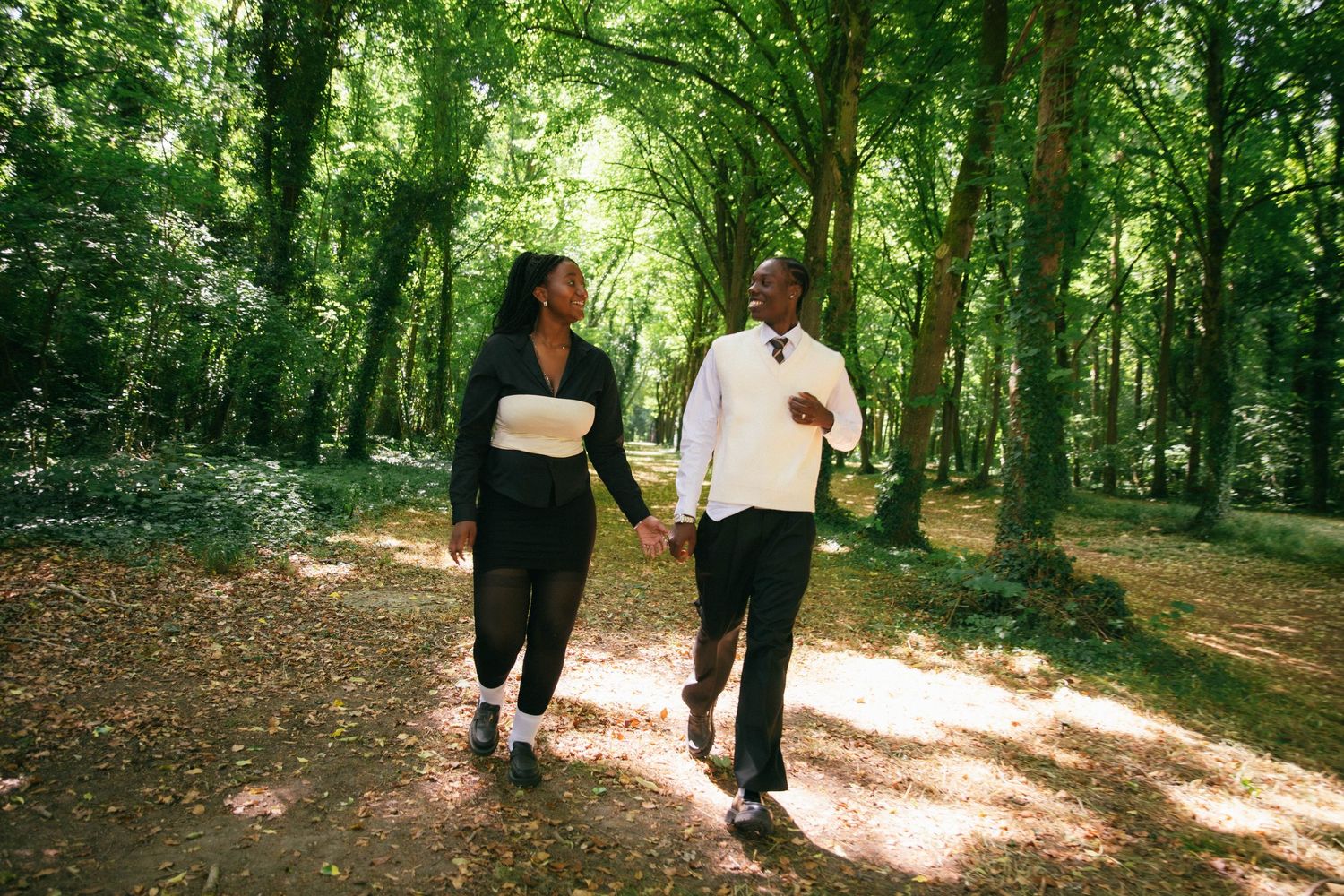 Séance photo couple complice se promenant main dans la main en forêt ensoleillée, photographe couple Essonne 91