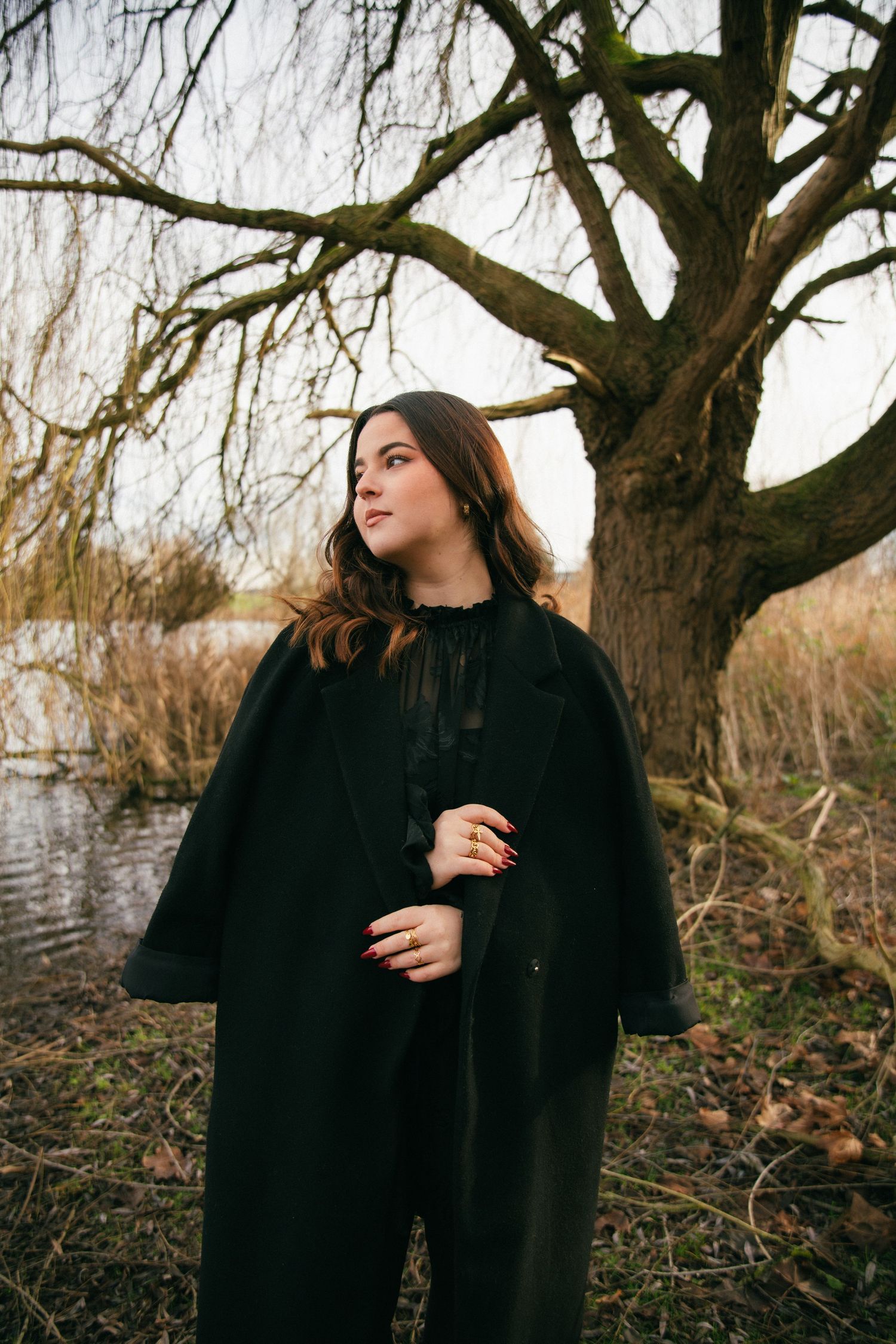 Photographe Essonne 91, portrait de jeune femme au manteau sombre regardant l'objectif, ambiance hivernale et naturelle au bord de l'eau