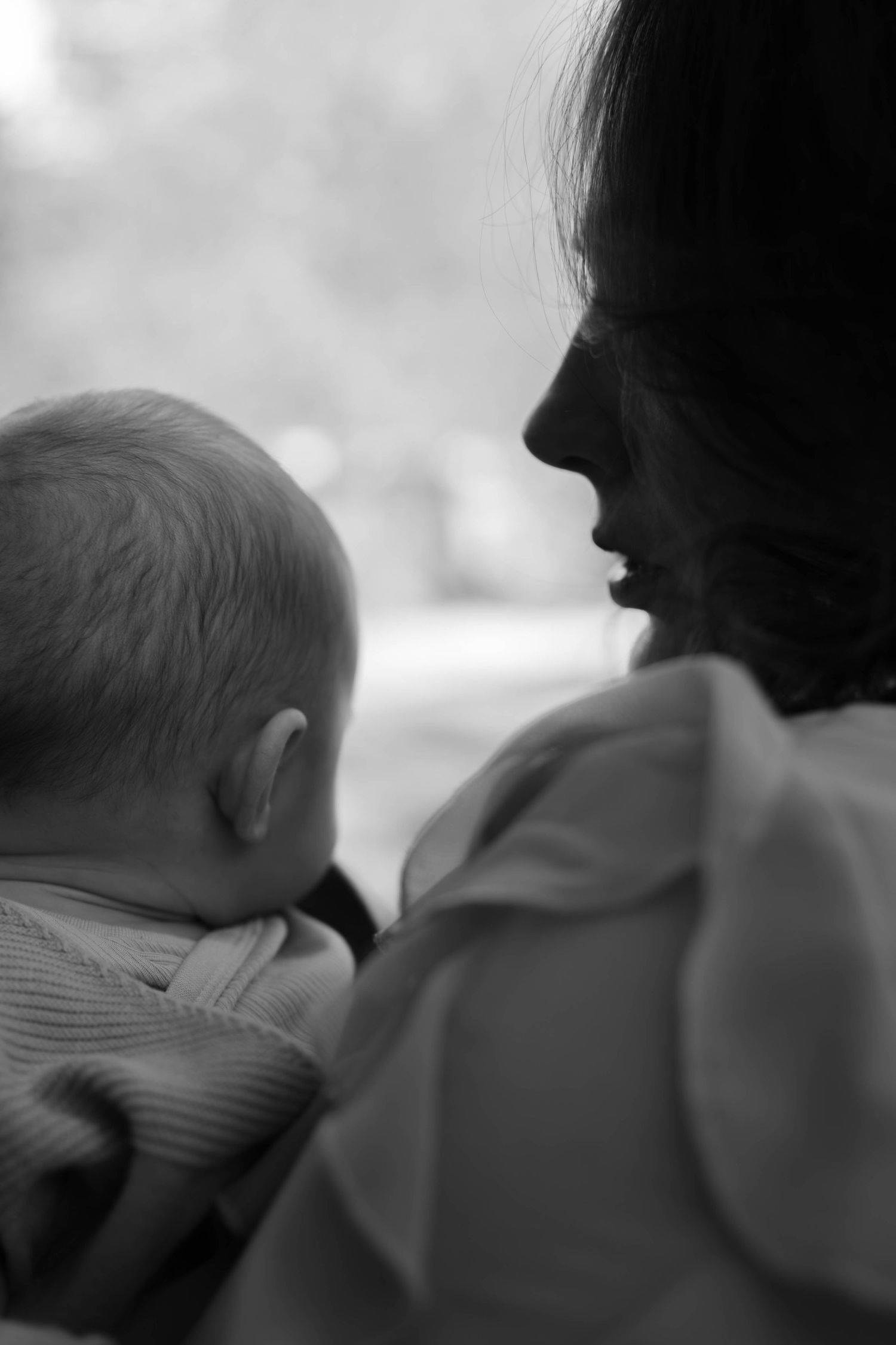 Séance photo naissance Essonne 91, maman tenant tendrement son nouveau-né dans les bras, portrait noir et blanc émouvant et intime