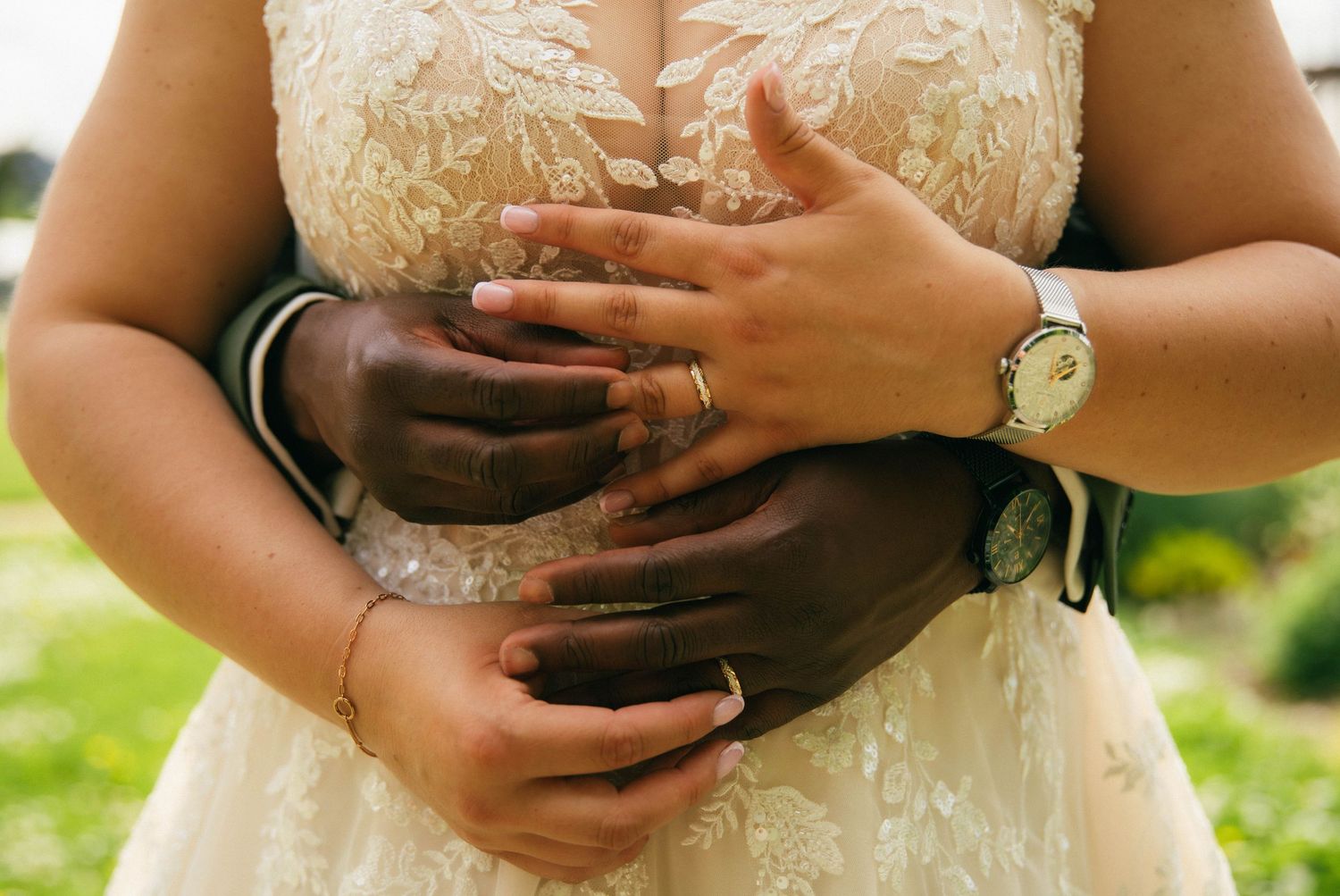 Photographe mariage Essonne 91, mains enlacées des mariés avec alliances, détail robe de mariée en dentelle, reportage mariage intime et émo