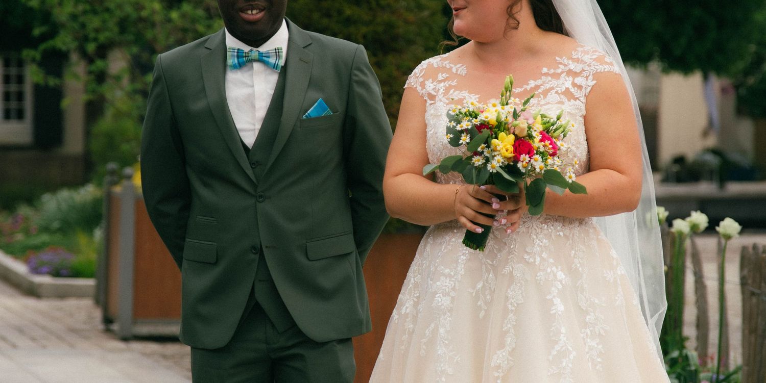 Photographie de mariage en extérieur à Orléans montrant les mariés côte à côte, avec un bouquet coloré et une ambiance élégante et naturelle