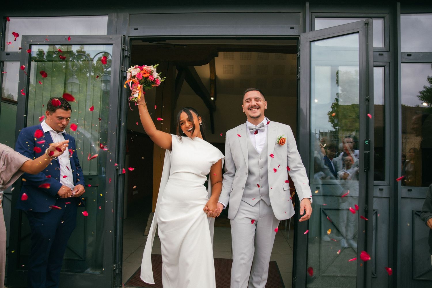 Sortie des mariés sous une pluie de pétales de roses rouges, sourires et joie au programme. Reportage mariage en Essonne. Photographe 91.