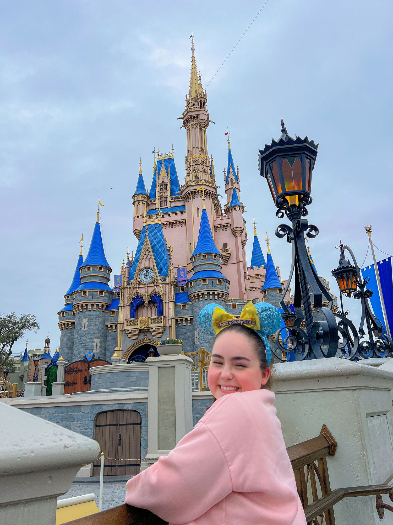 Une visiteuse pose devant le château emblématique de Disneyl World, symbole du parc et de la magie Disney.