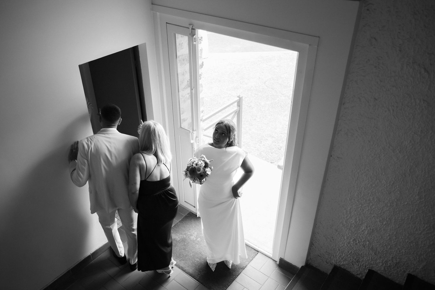 Photographe mariage Essonne 91, mariée et proches vus de dessus attendant devant la porte avant la cérémonie, noir et blanc,