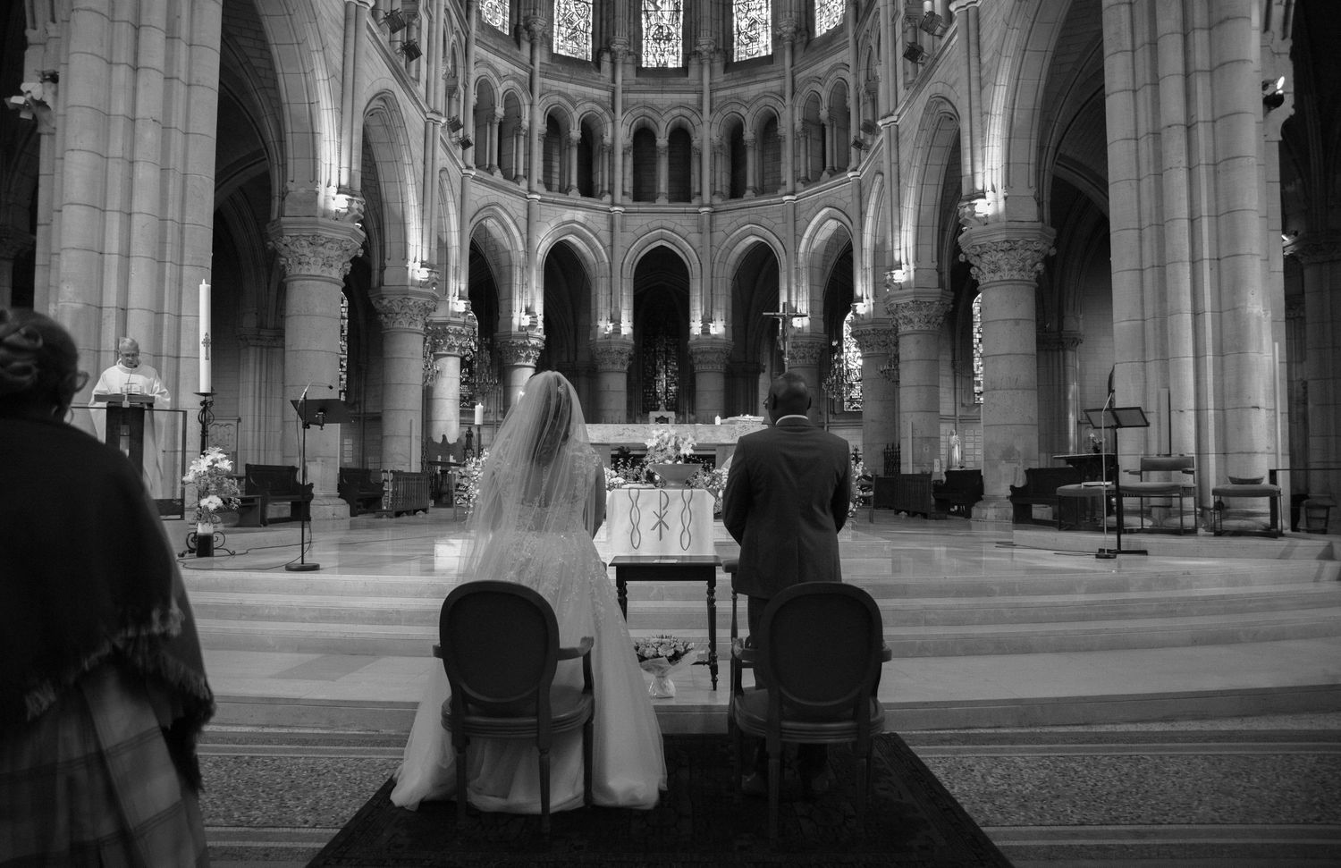 Cérémonie religieuse en noir et blanc : mariés à l'autel de la cathédrale d'Orléans, sous les arches majestueuses. Photographe mariage 91.