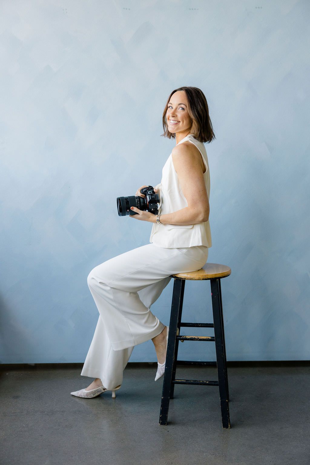 Michigan Photographer poses in a Lansing studio with blue wall