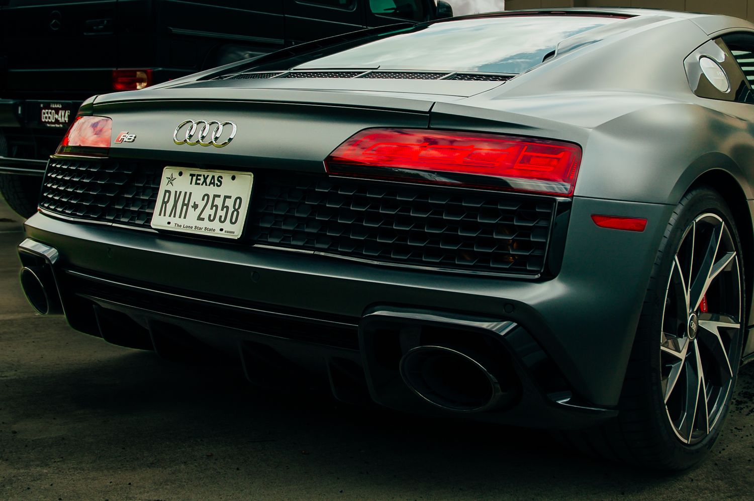 Rear view of matte gray Audi R8 V10 with Texas license plate and dual exhausts.