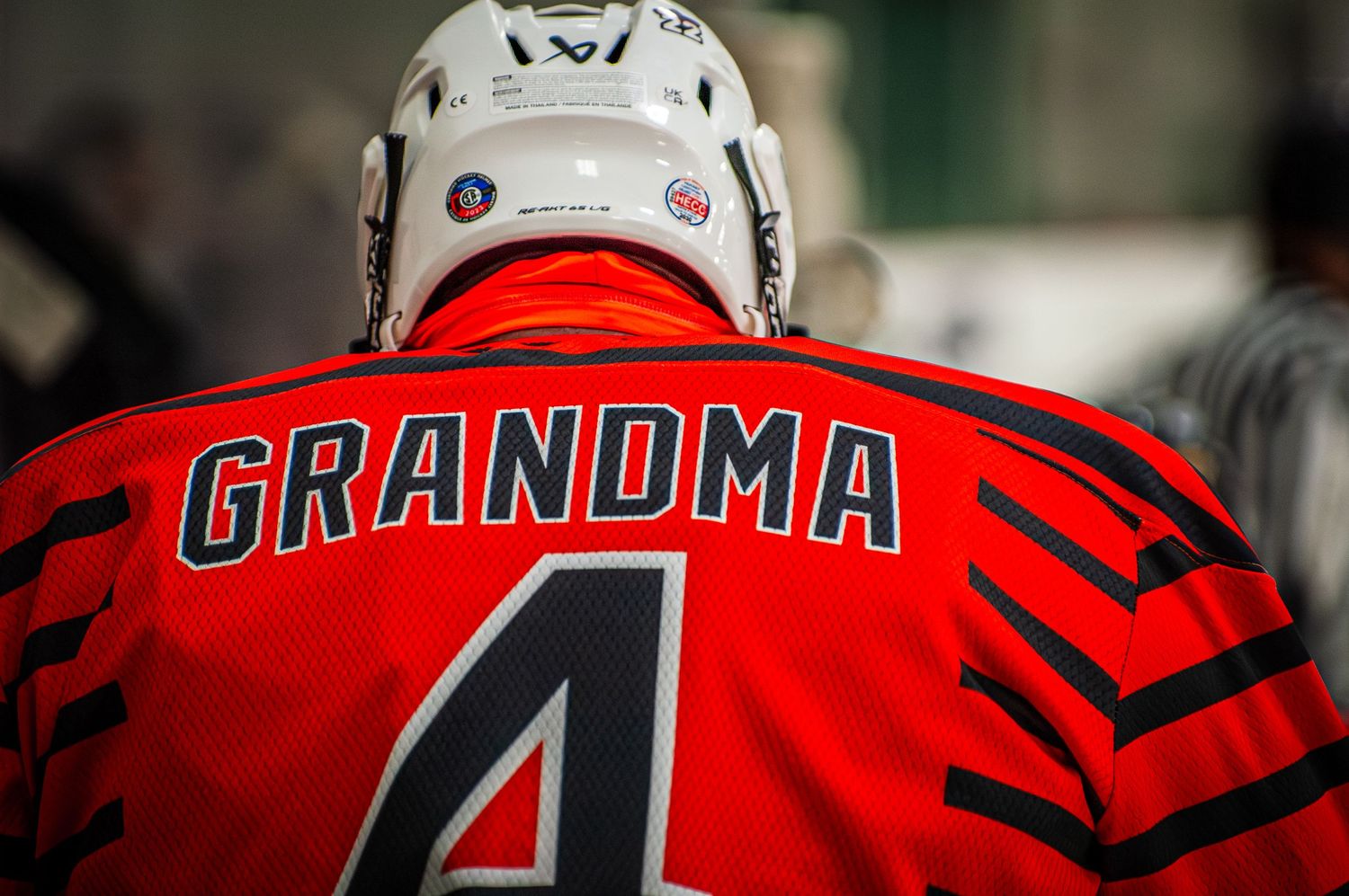 Hockey player wearing red jersey with GRANDMA number 4 on the back during an ice hockey game.