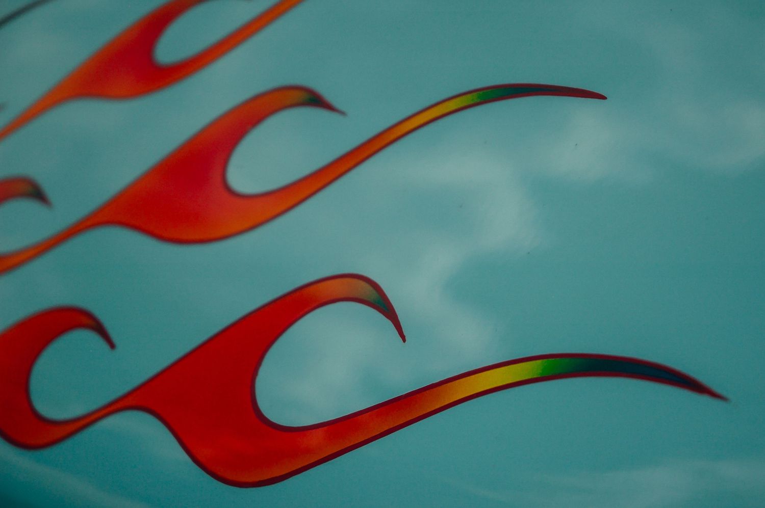 Red and orange flame custom pinstripe artwork on a turquoise classic car hood panel.