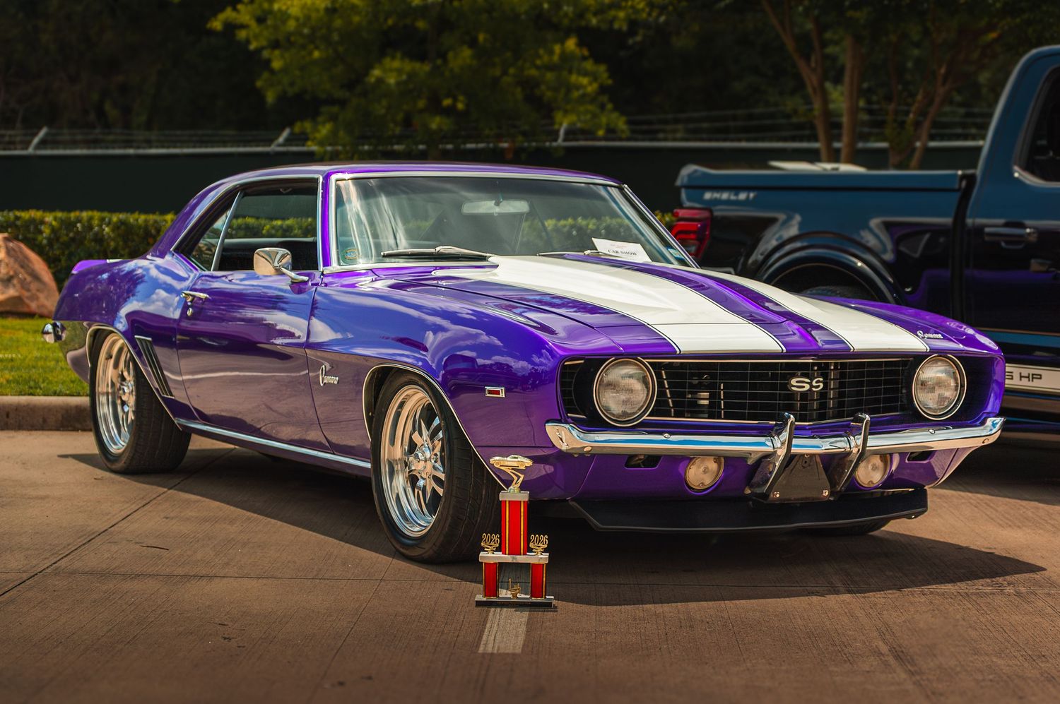 Award-winning purple 1969 Chevrolet Camaro SS with white racing stripes at car show.