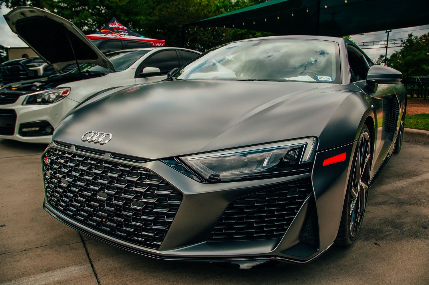 Matte gray Audi R8 supercar on display at an outdoor automotive car show event.