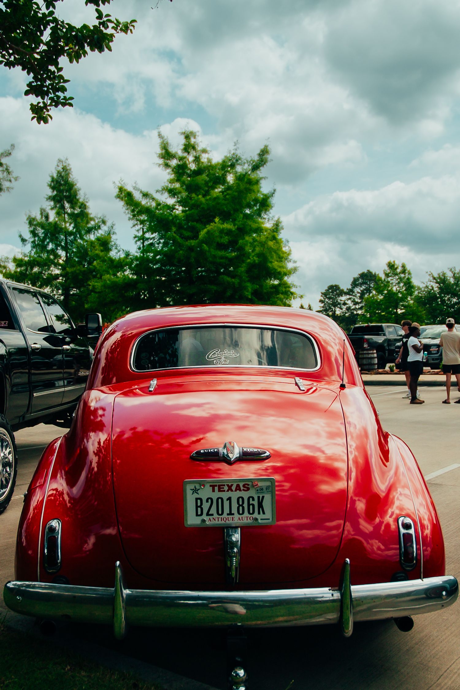 Rear view of a red vintage Texas classic car with chrome bumper and period license plate.