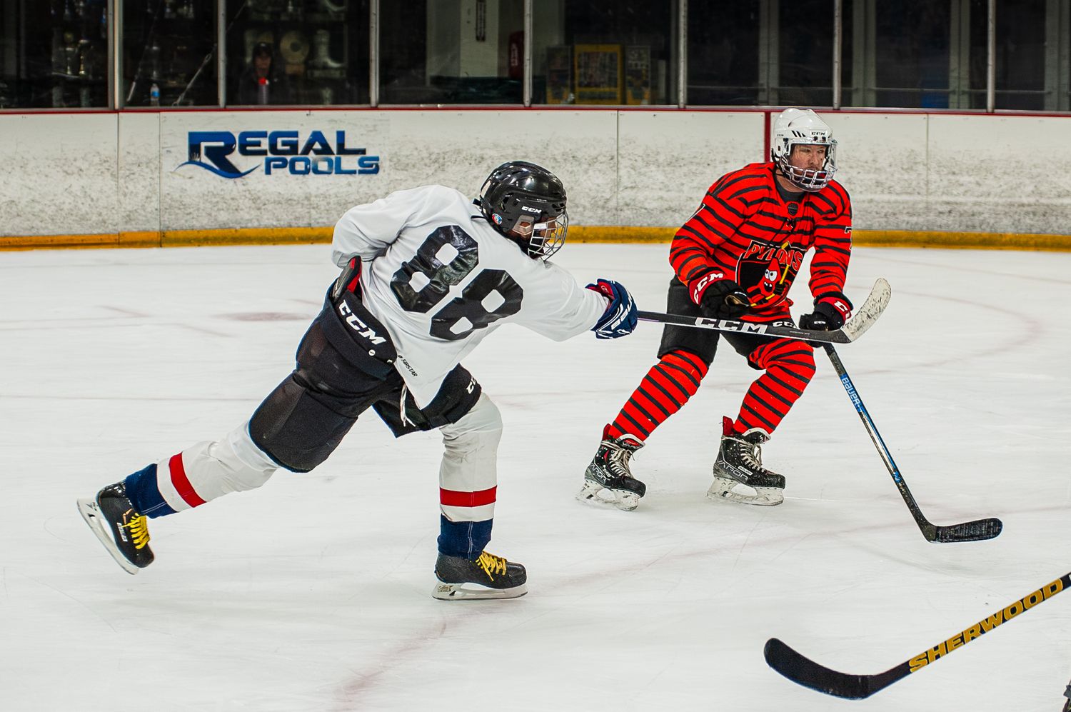 Two ice hockey players competing for puck during game at Regal Pools arena.
