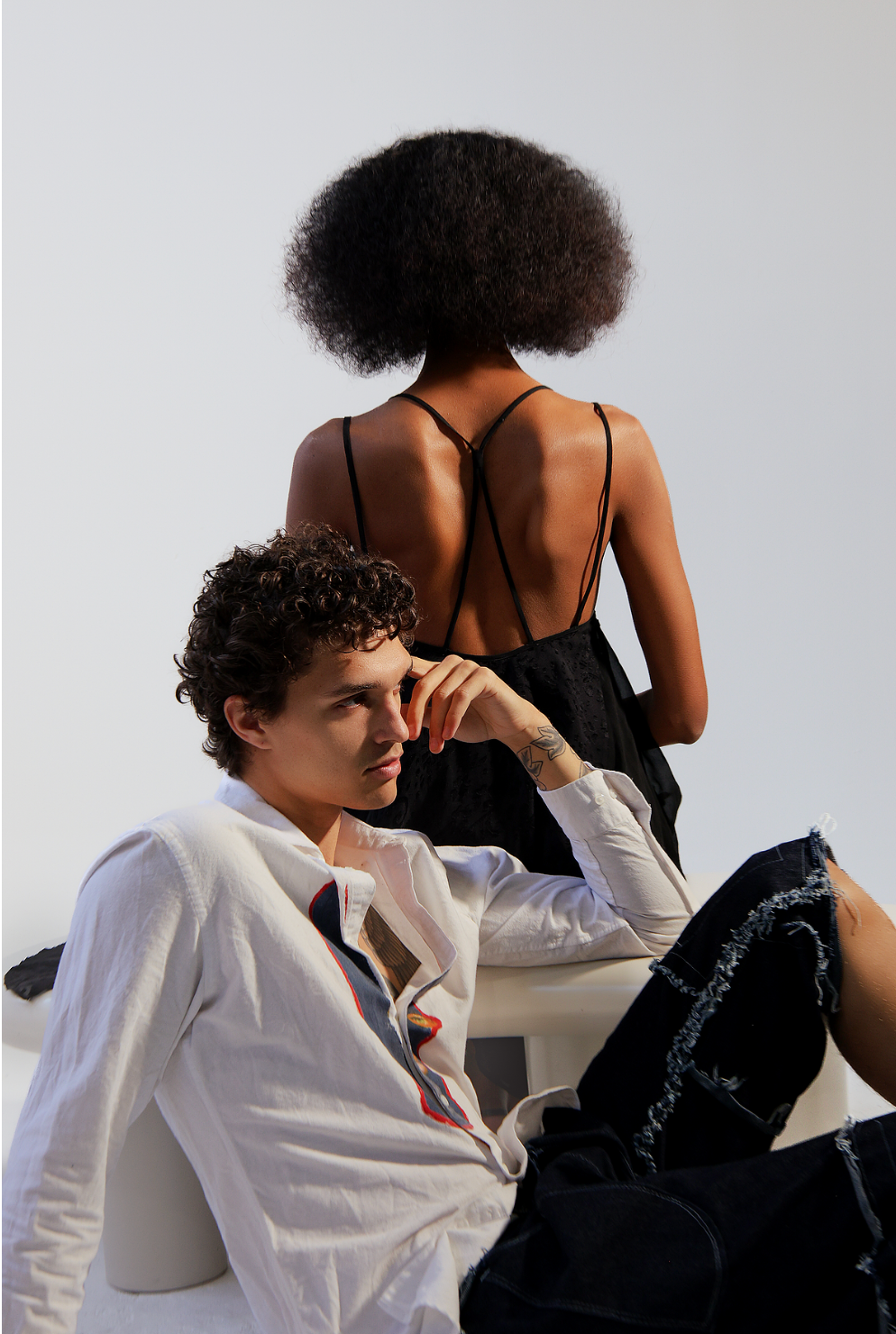 Woman has back turned while a man sits in front of her pensively posing and facing ahead