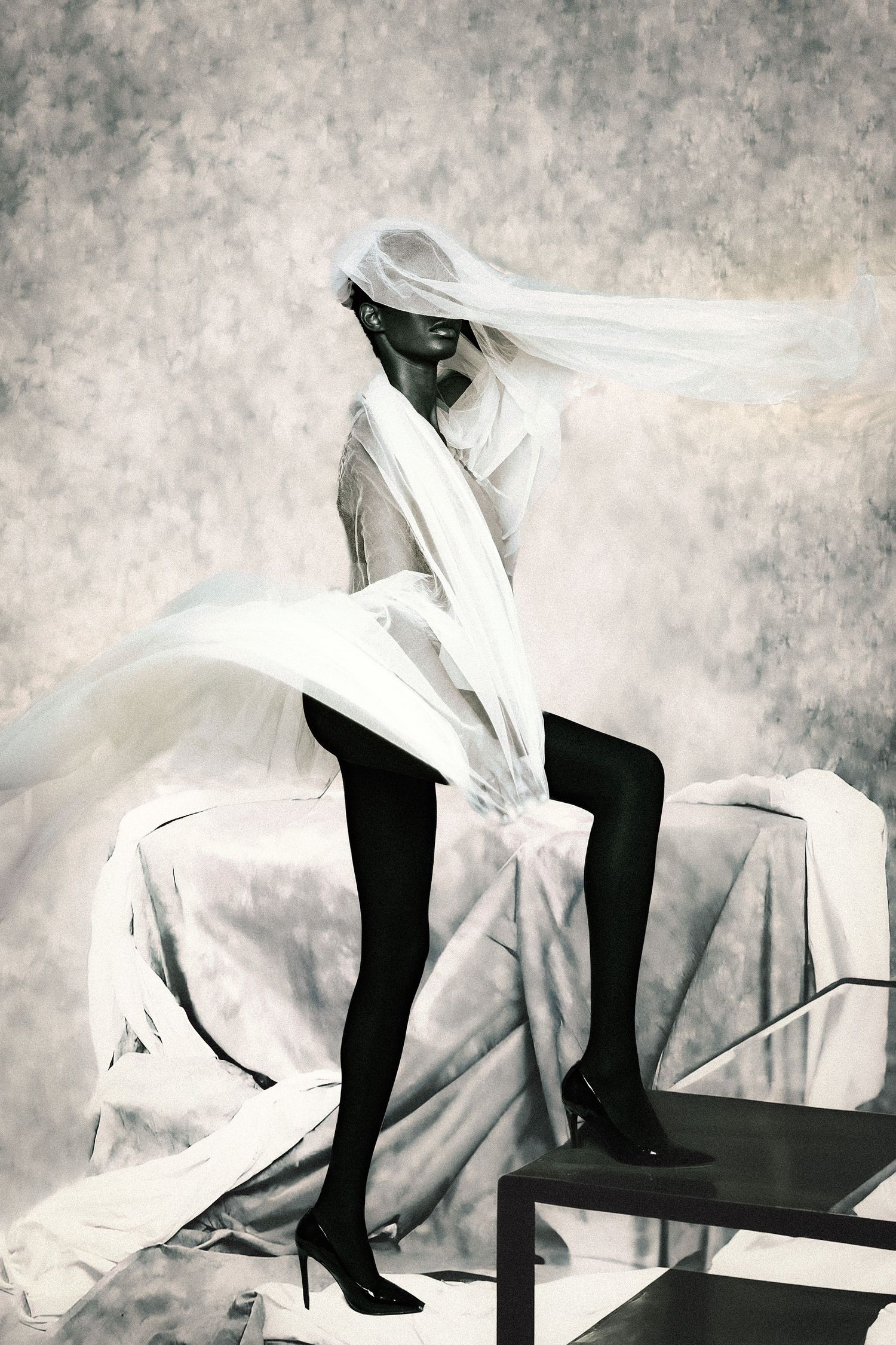 Woman covered face in white sheet wearing black tights in editorial composition