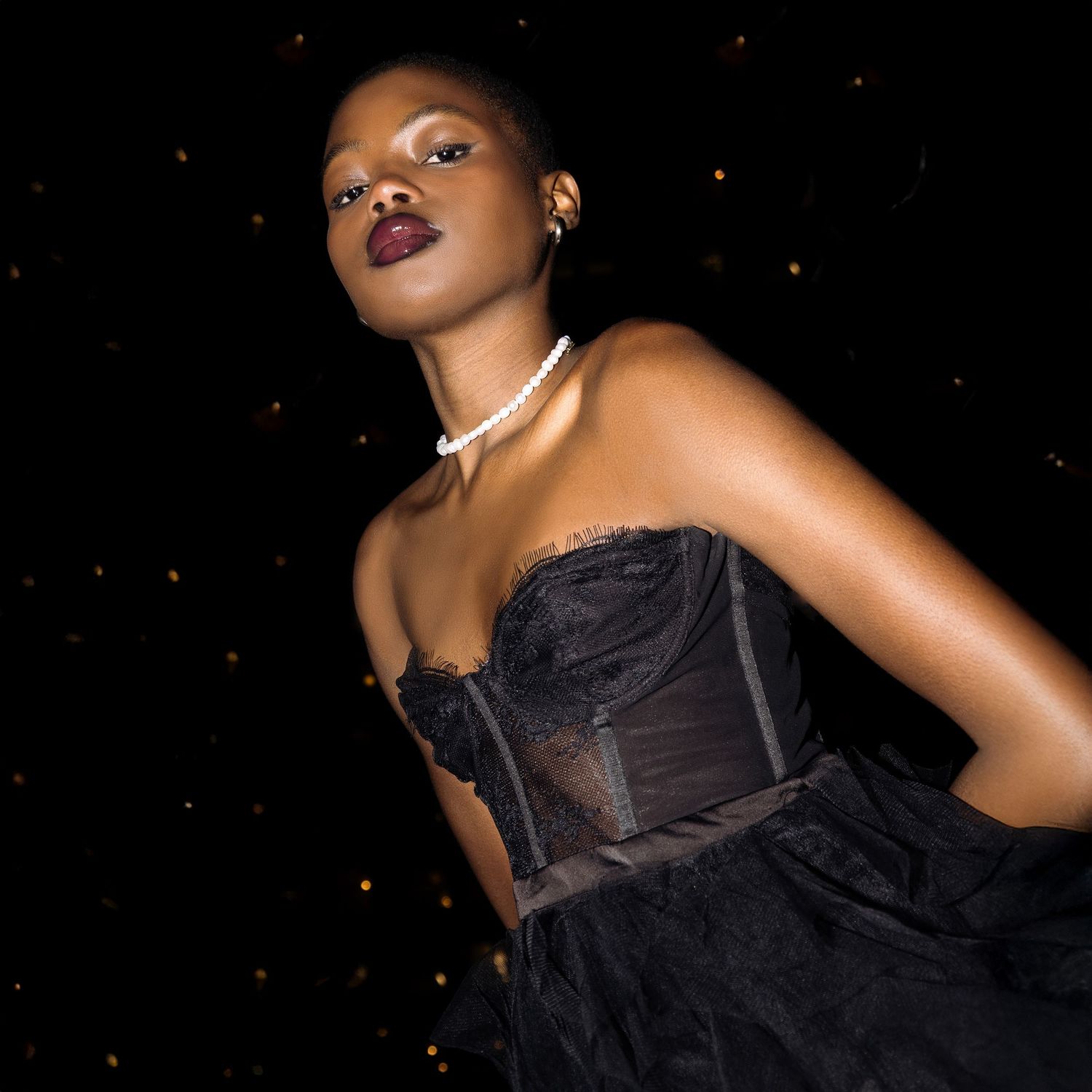 Woman posing in black dress and pearls looking powerful