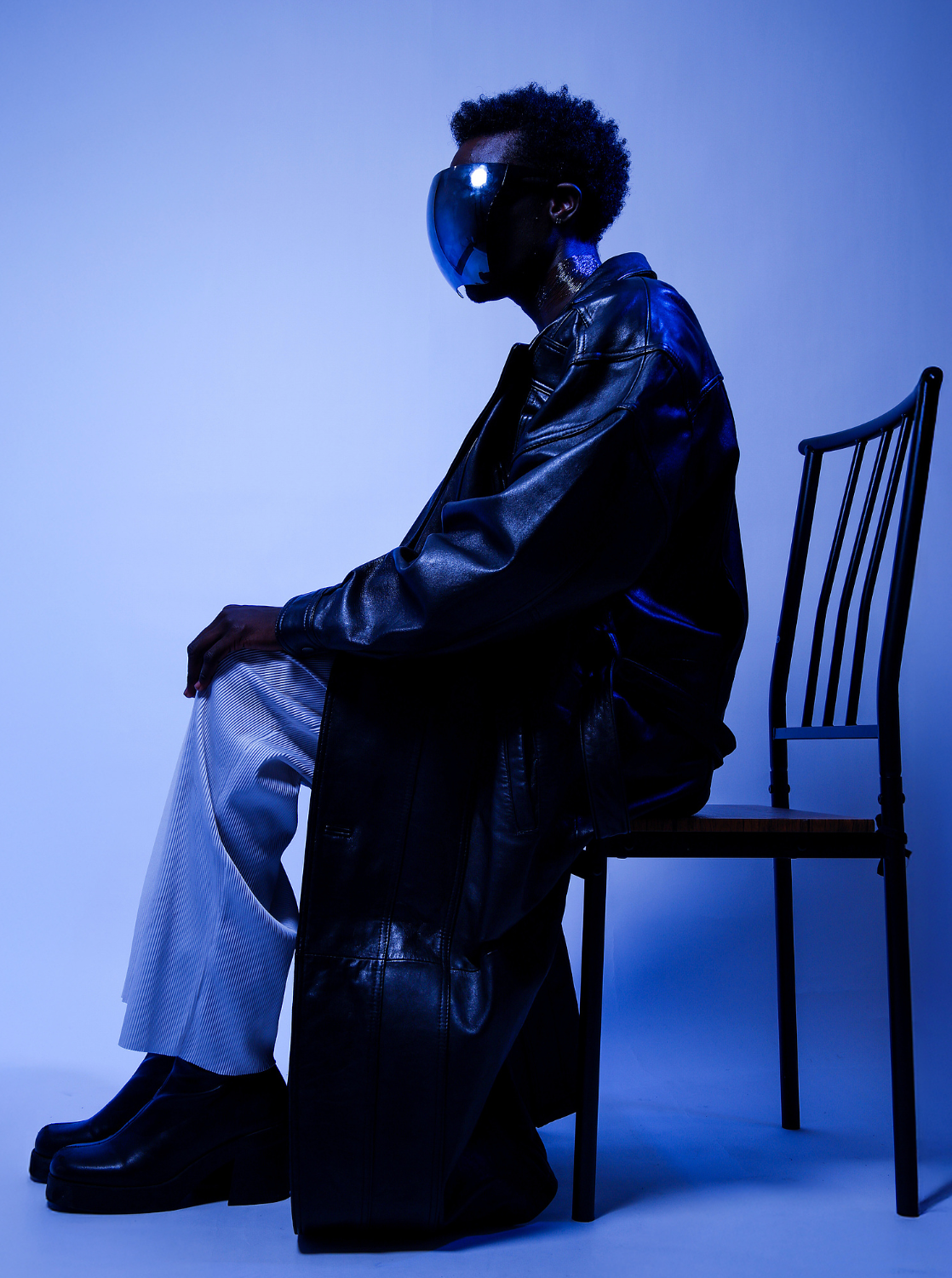 Blue atmosphere containing boy with a space mask sitting tall in a chair