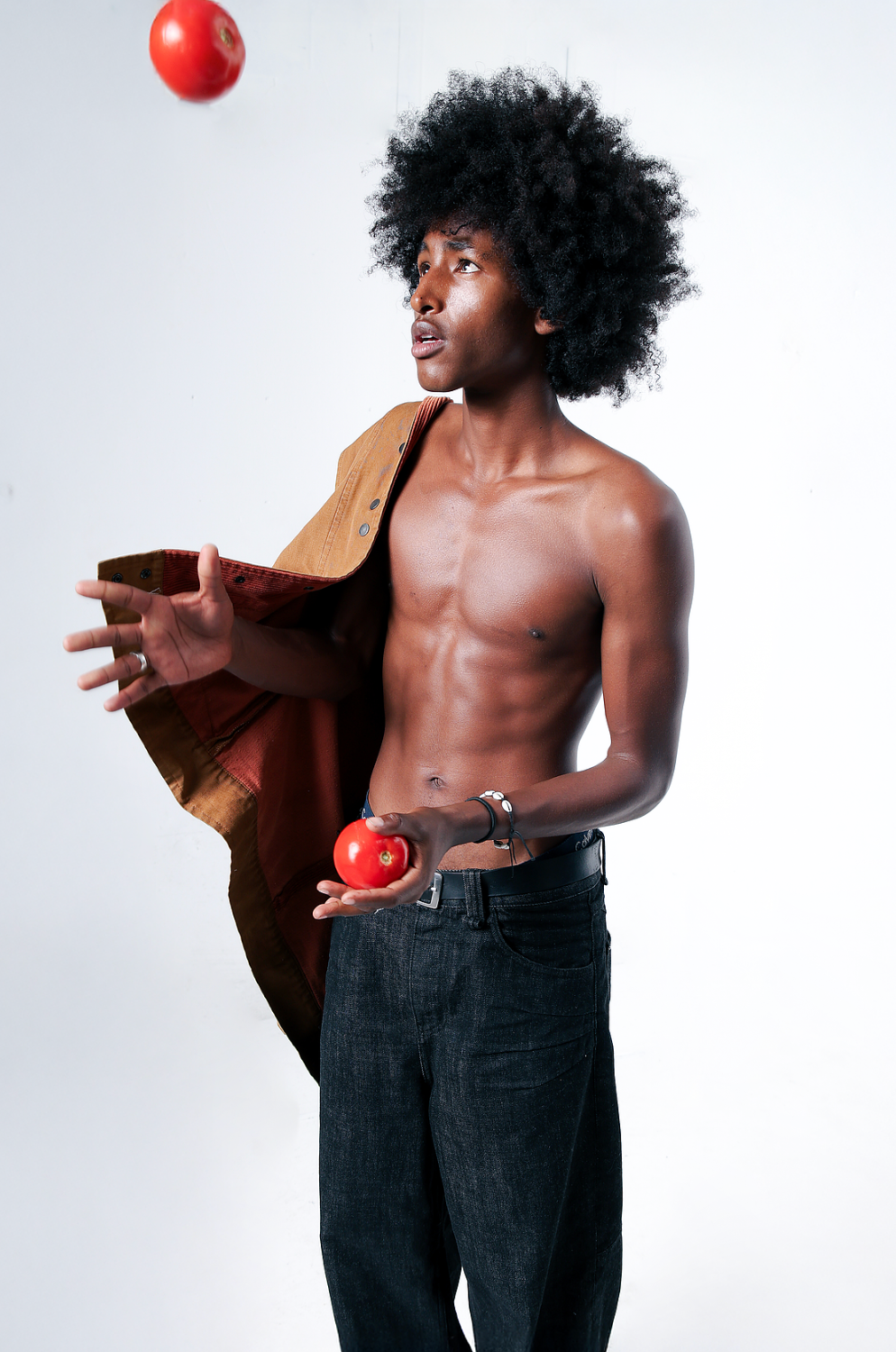 Man juggling tomatoes in a light brown and red corduroy jacket