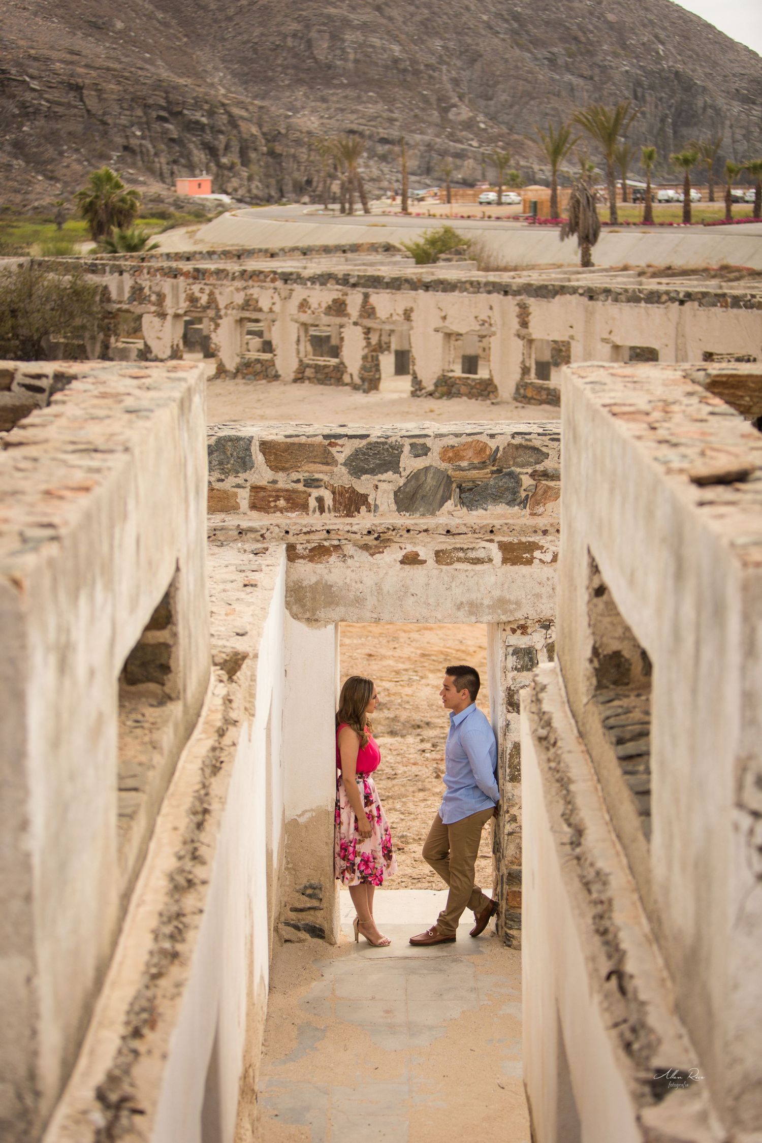 Couple standing together in ancient stone ruins with a mountain backdrop during an engagement shoot.