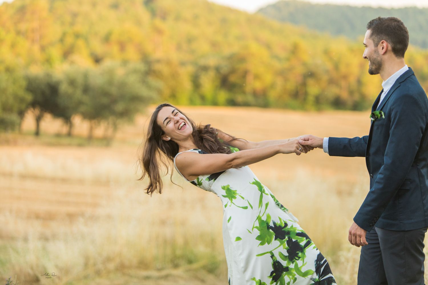 Joyful couple spinning and laughing together in a golden autumn field outdoors.