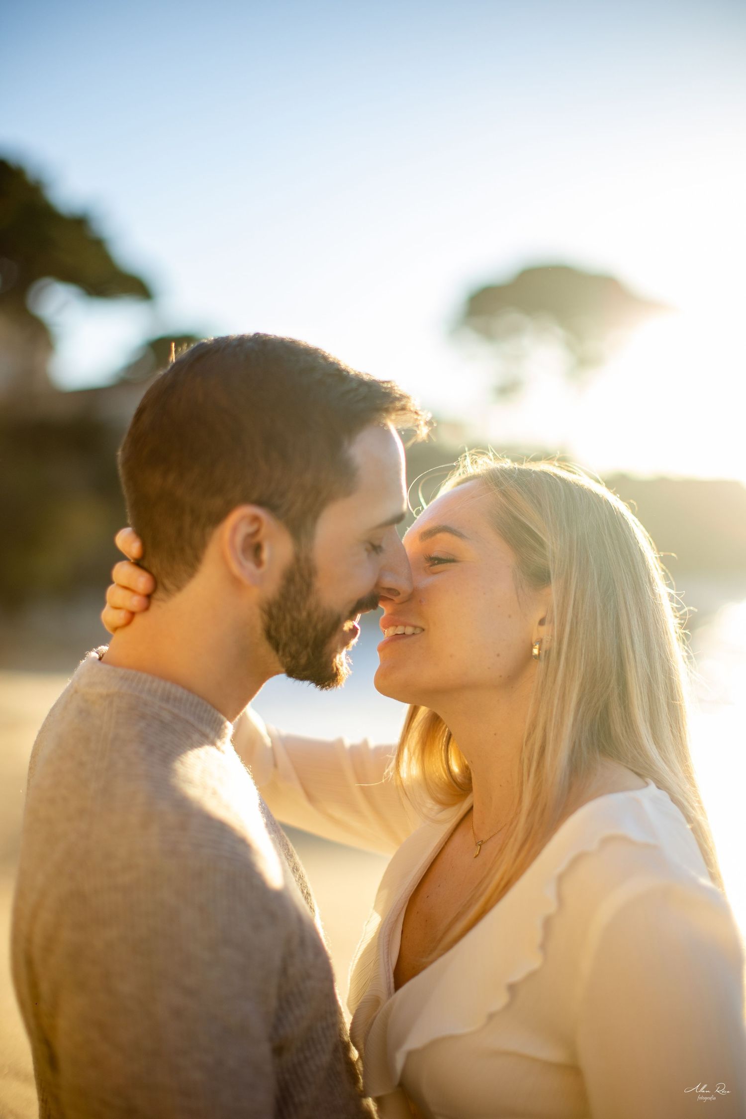 Couple sharing a tender almost-kiss moment on a sun-drenched beach.