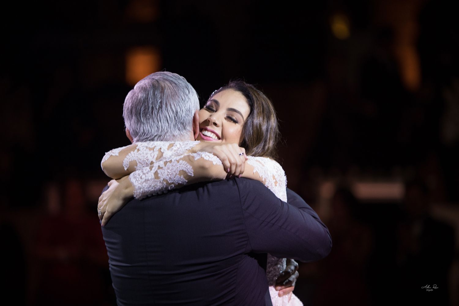 Bride sharing a warm embrace with father during emotional wedding reception moment.