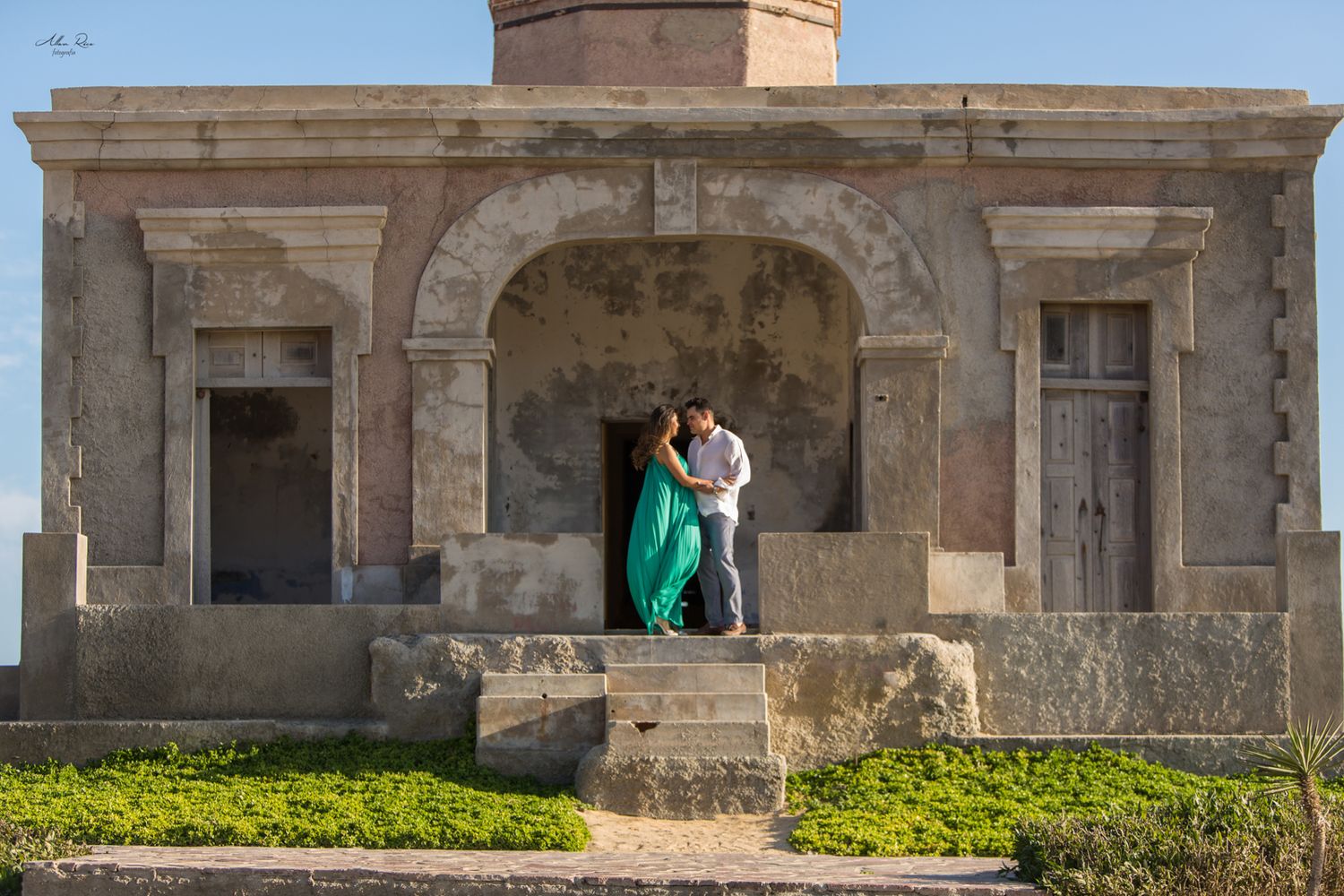 Couple kissing in the archway of a rustic historic building with teal dress flowing.