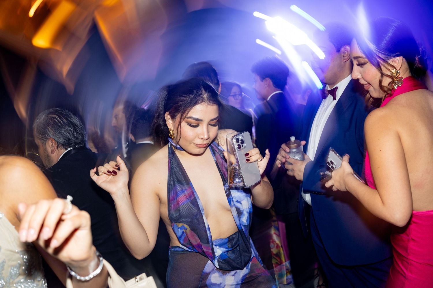Guest in a colorful plunging dress dancing energetically at a vibrant wedding reception party.