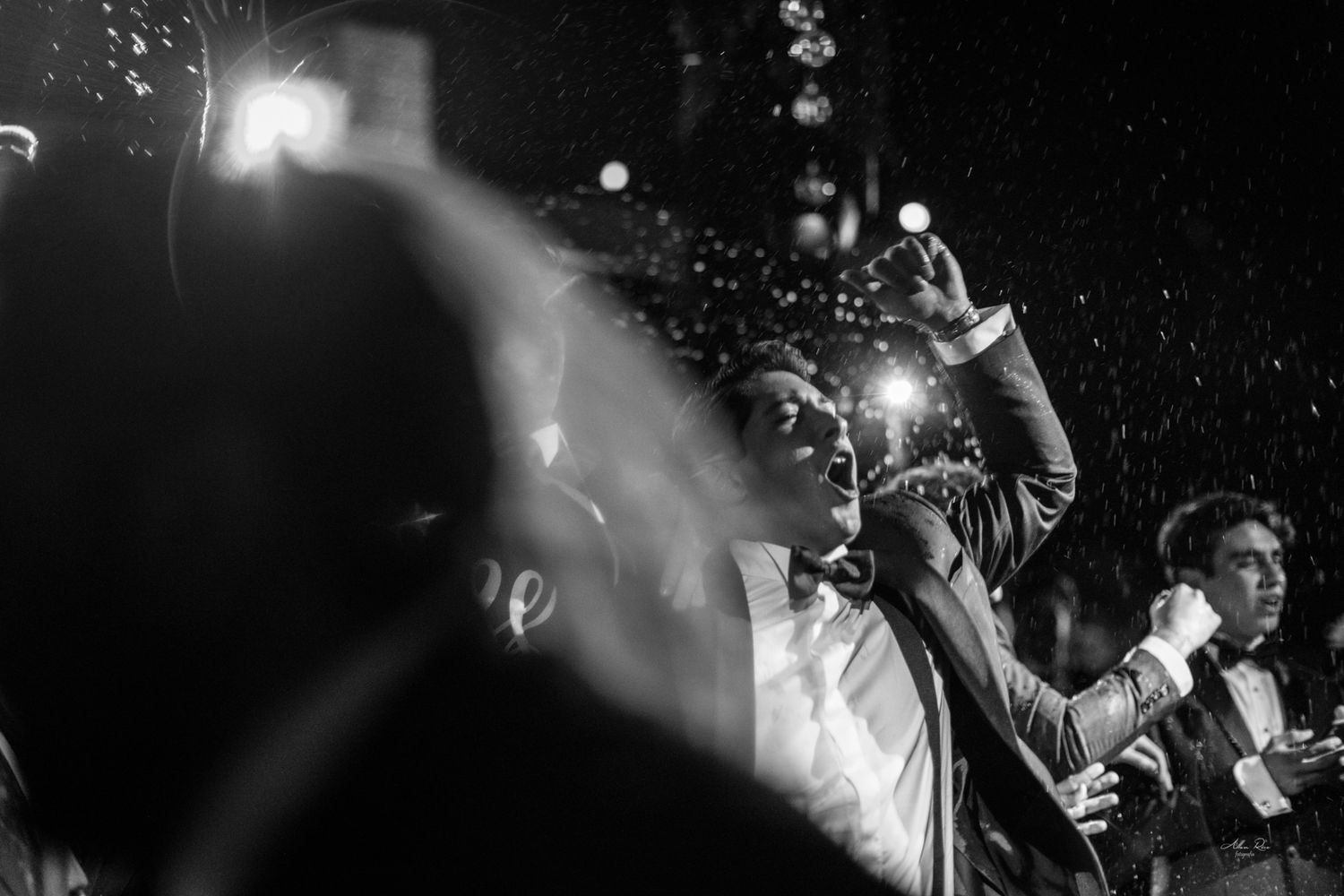 Guest capturing moments on phone at lively nighttime wedding reception.